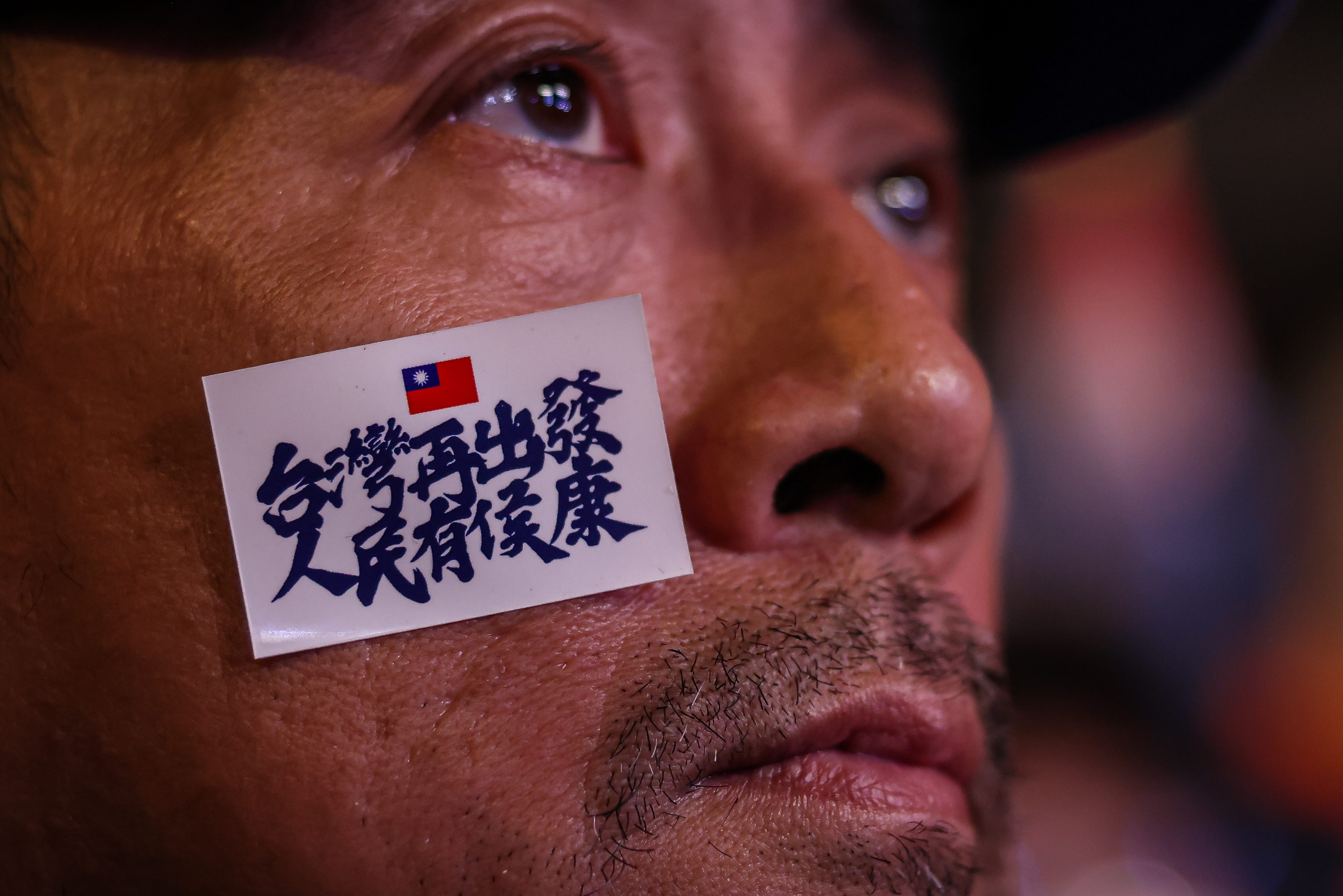 Ein Anhänger der Kuomintang (KMT) trägt während einer Kundgebung am Vorabend der Parlamentswahlen am 12. Januar 2024 in Taipeh, Taiwan, einen Wahlkampfslogan im Gesicht.