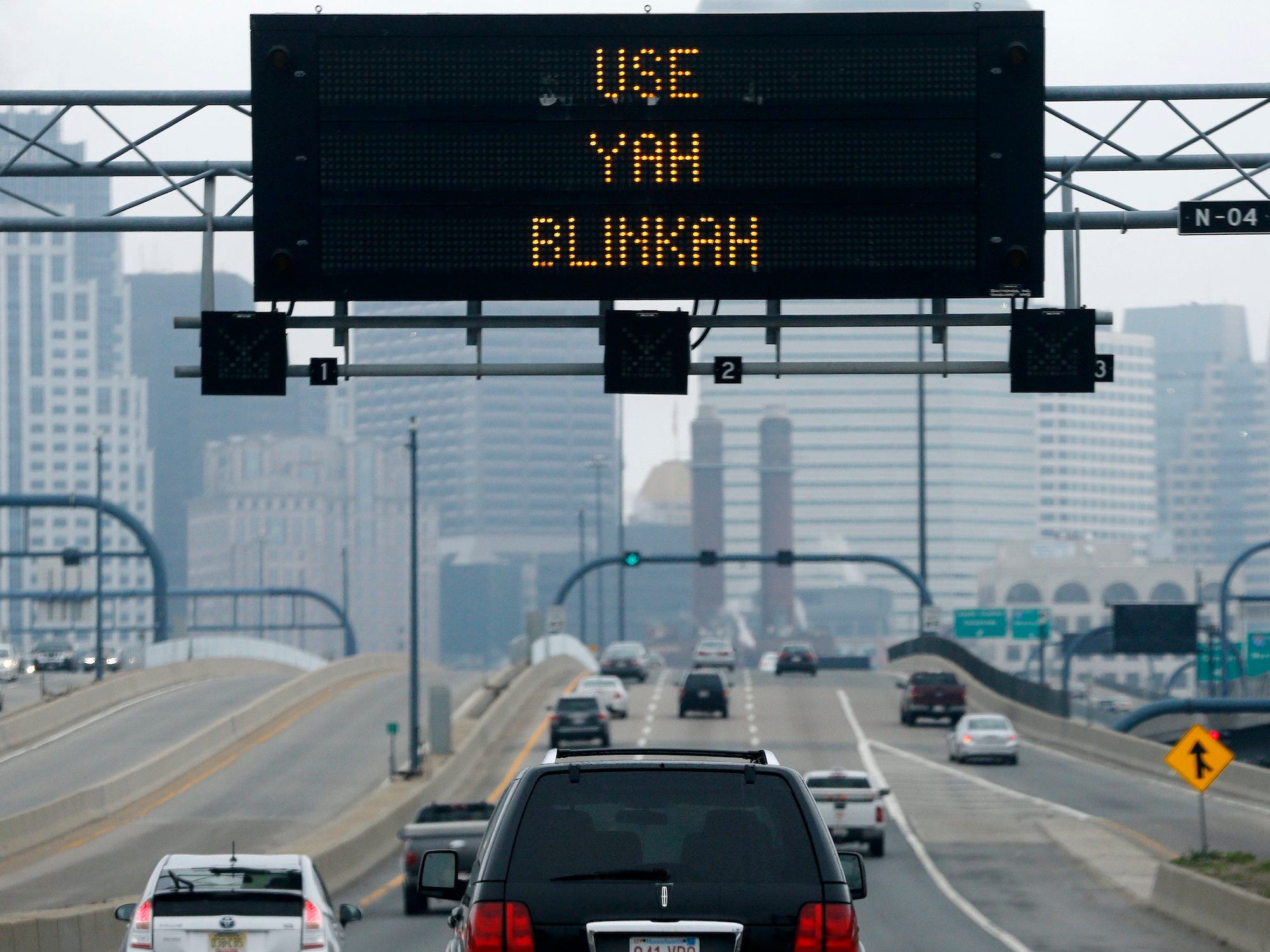 Großes schwarzes elektronisches Schild mit der Aufschrift „Use yah blinkah“ über einer Autobahn mit Autos