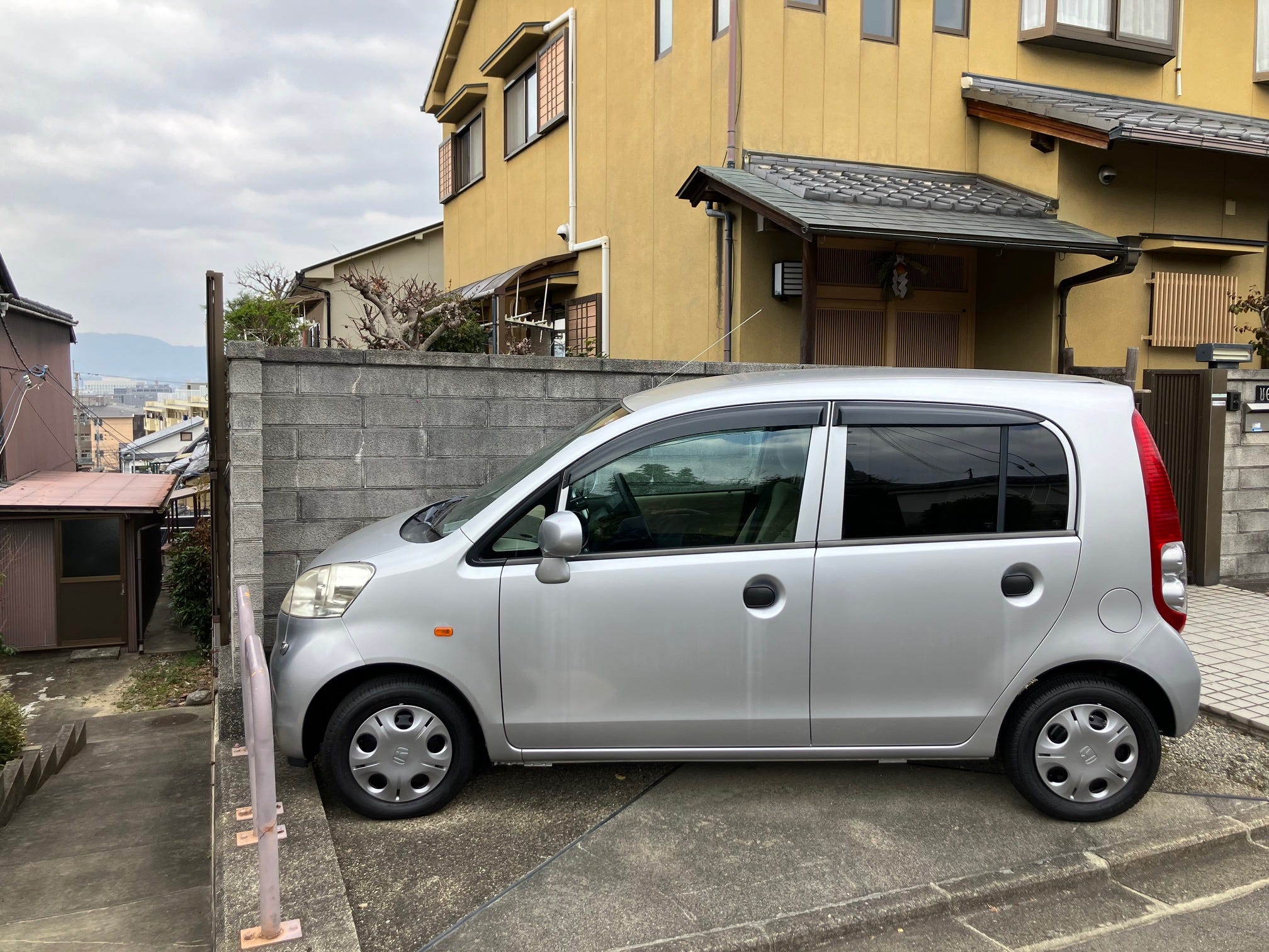 Ein Honda Life Kei-Auto parkte in einer kleinen Einfahrt in Japan