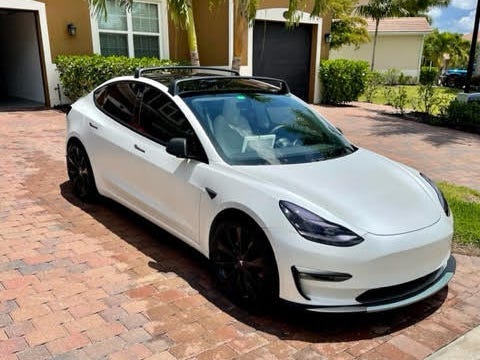 Ein perlweißer Tesla Model 3 parkte in einer Einfahrt