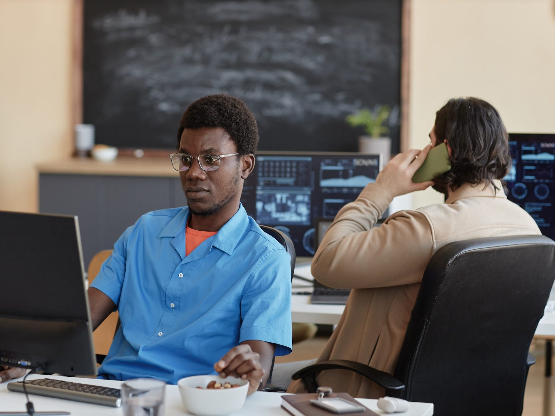 Ein Ingenieur arbeitet und schaut auf einen Computer, während eine andere Person telefoniert