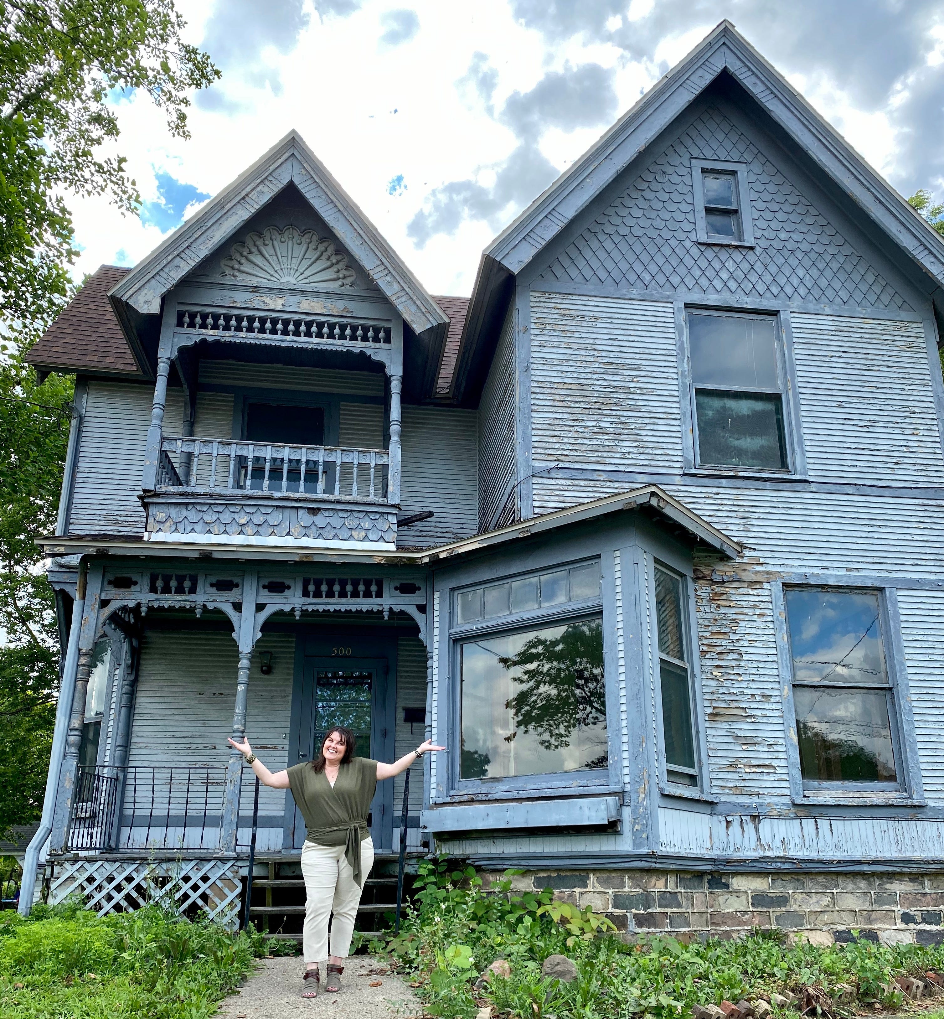 Eine Frau steht vor einem heruntergekommenen viktorianischen Herrenhaus aus den 1890er Jahren in Indiana.