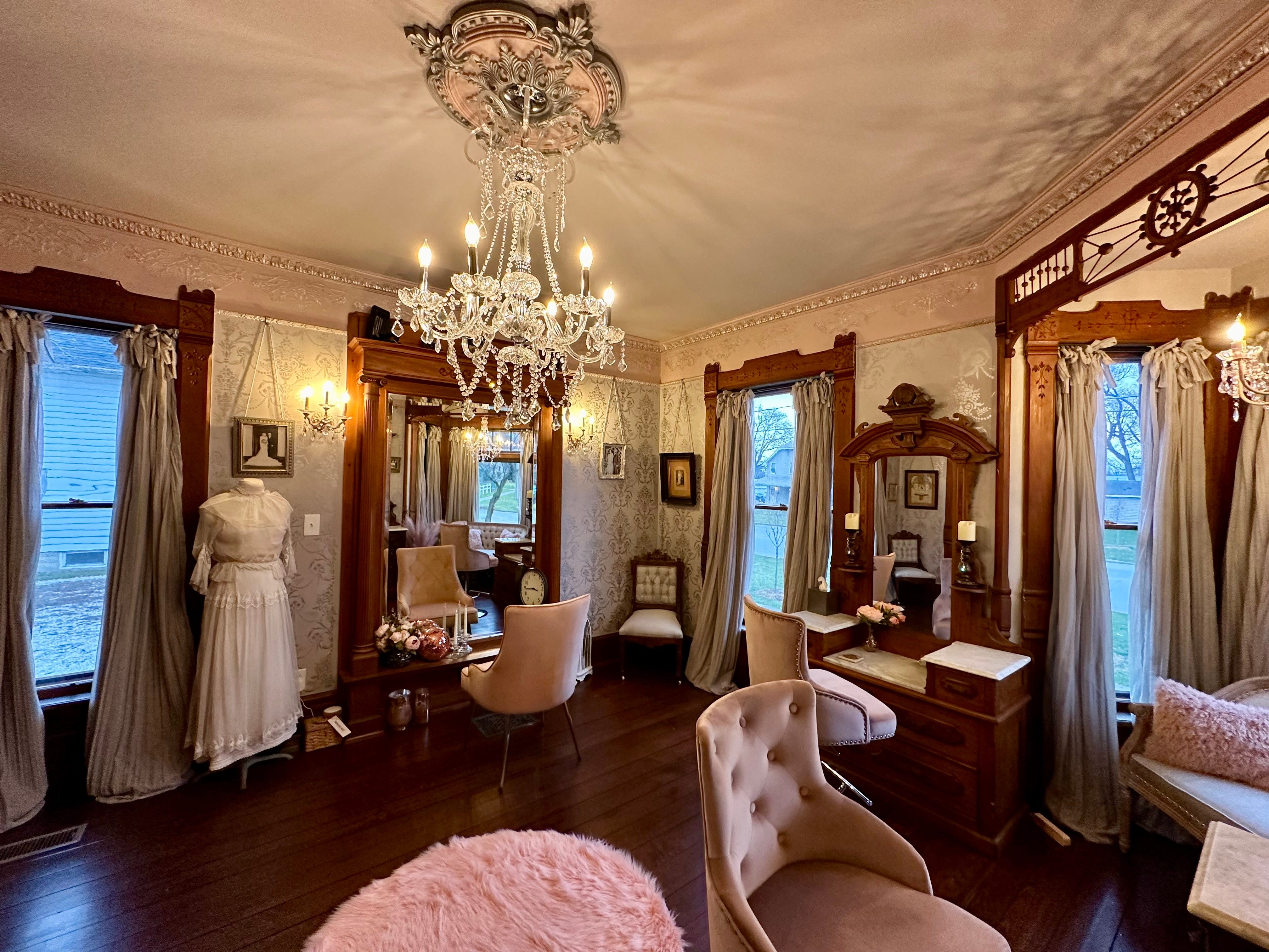 Ein Salon, der mit ausgefallenen Möbeln eingerichtet ist, darunter ein Kronleuchter, gemusterte Tapeten und Holzmöbel.