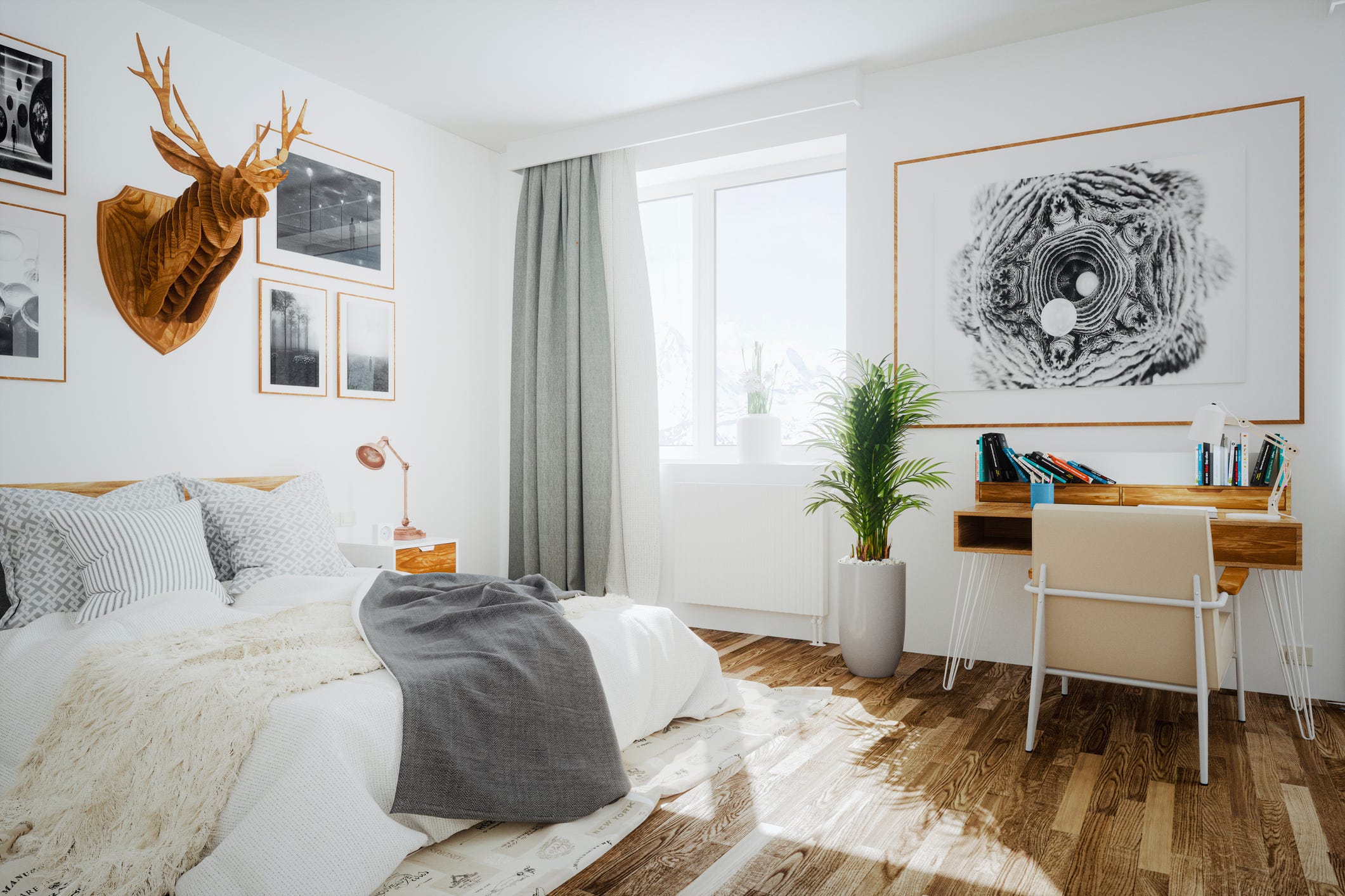 Weißes und luftiges skandinavisches Schlafzimmer mit 3D-Hirschkopfskulptur aus Holz an der Wand und kleinem Schreibtisch