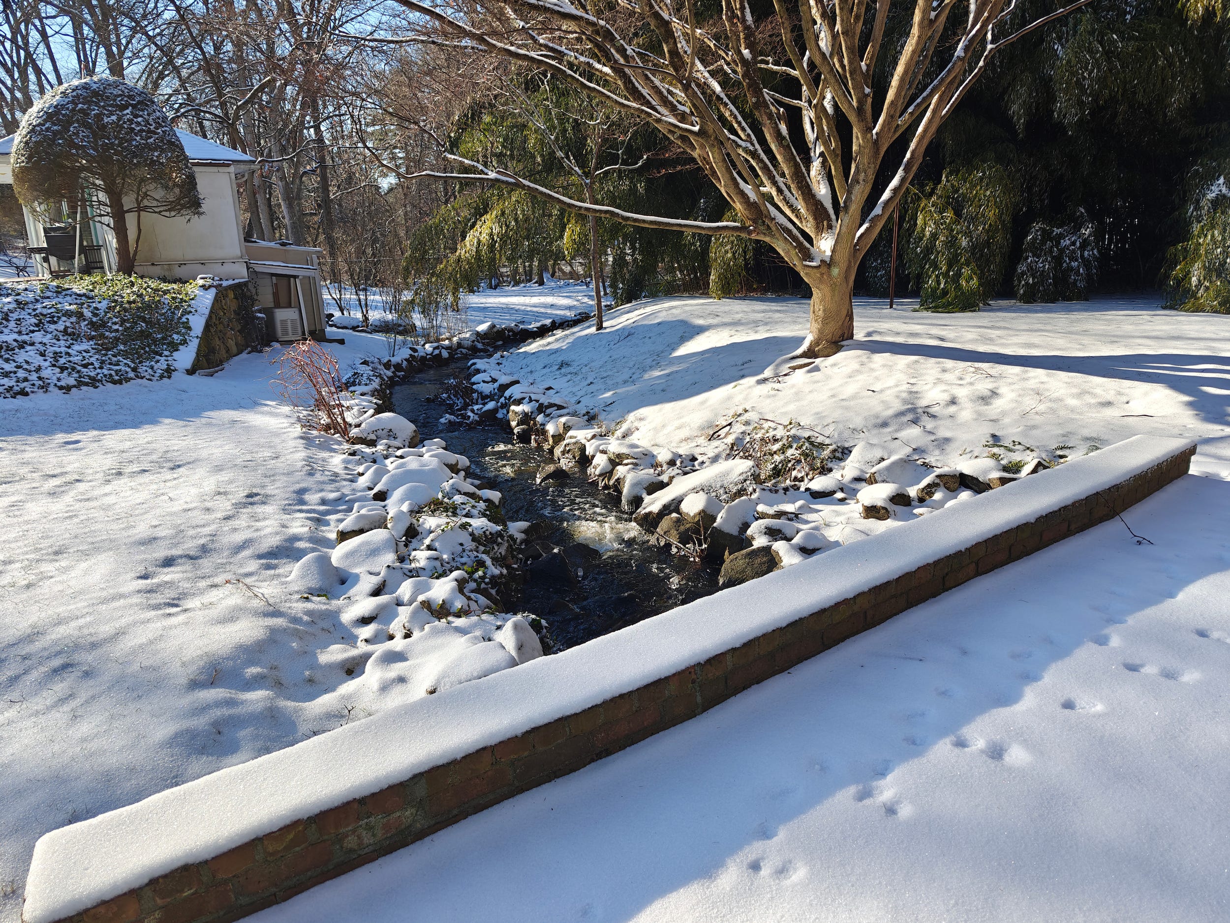 Ein Foto eines Baches, einer schneebedeckten Brücke und Felsen, aufgenommen mit der Hauptkamera des OnePlus 12.