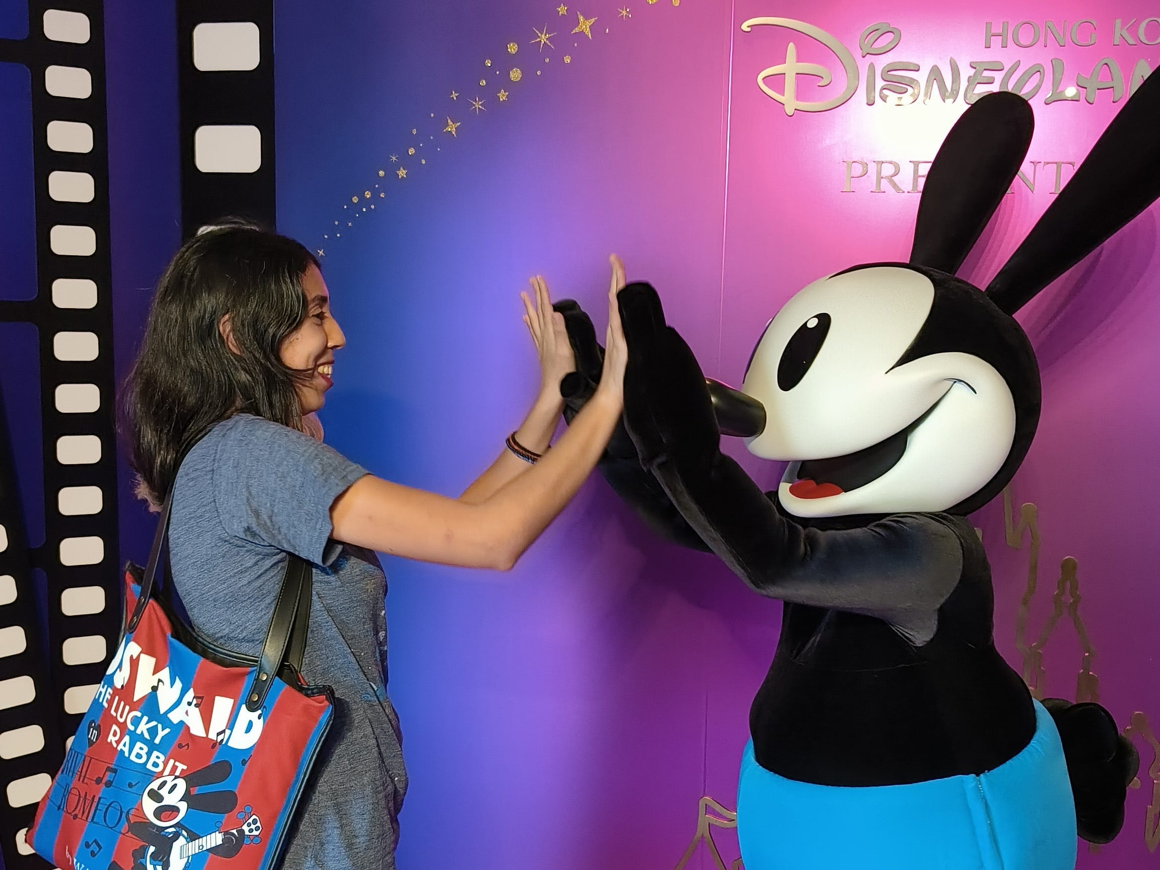 Frau gibt Mickey Mouse im Disneyland Hong Kong ein High-Five