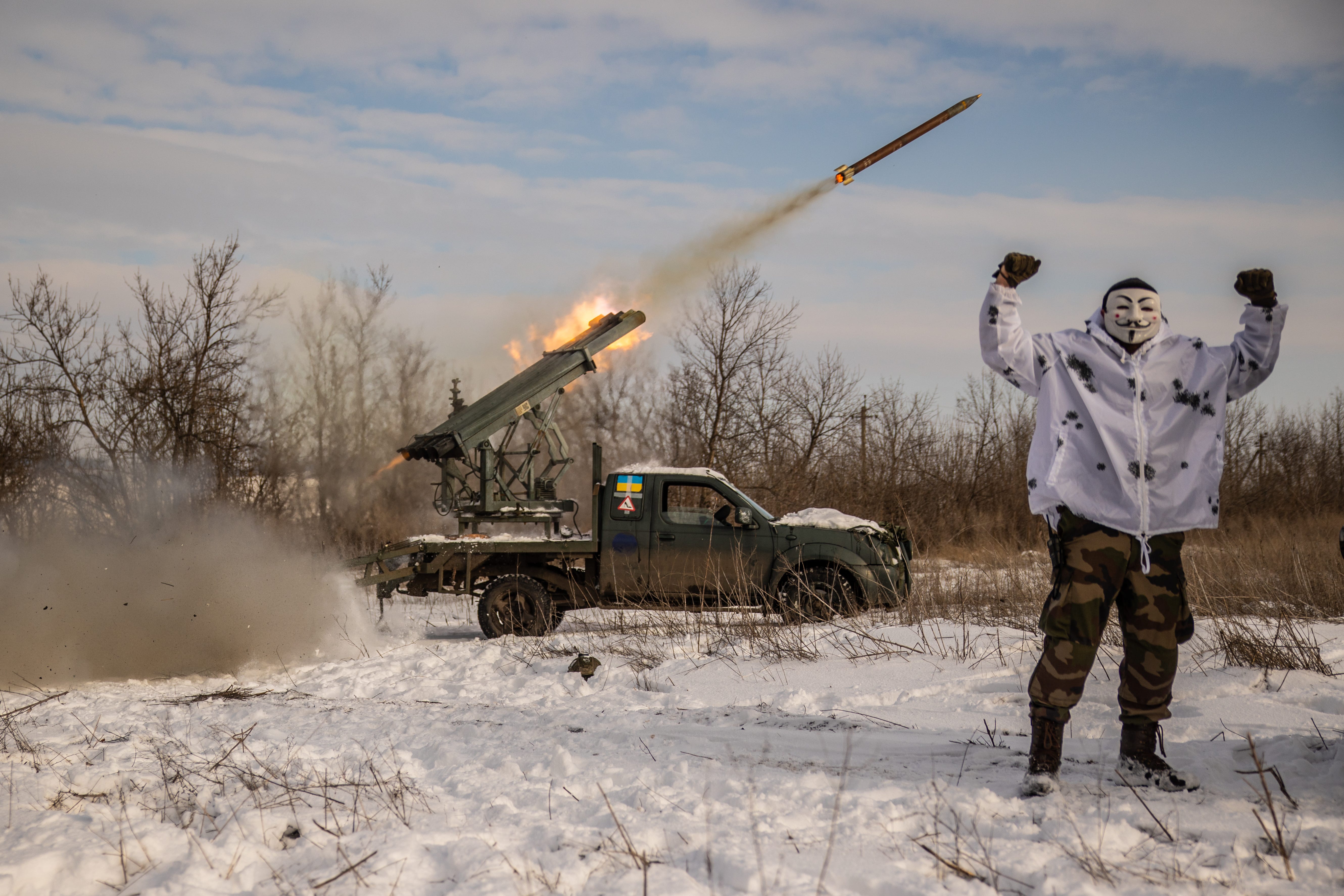 Ein ukrainischer Soldat mit Maske steht am 15. Januar 2024 in der Oblast Donezk in der Ukraine in der Nähe eines improvisierten Mehrfachraketenwerfers, während er auf russische Stellungen feuert.