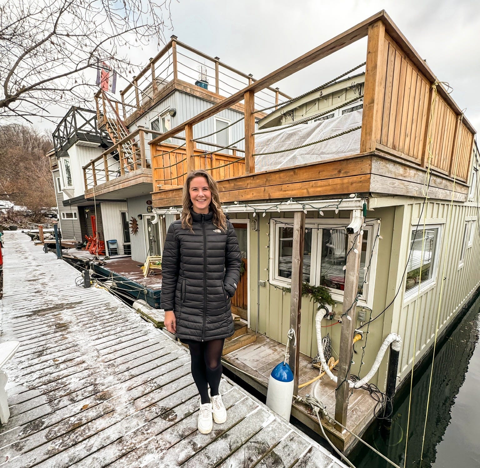 Eine Frau steht im Winter vor einem Hausboot.