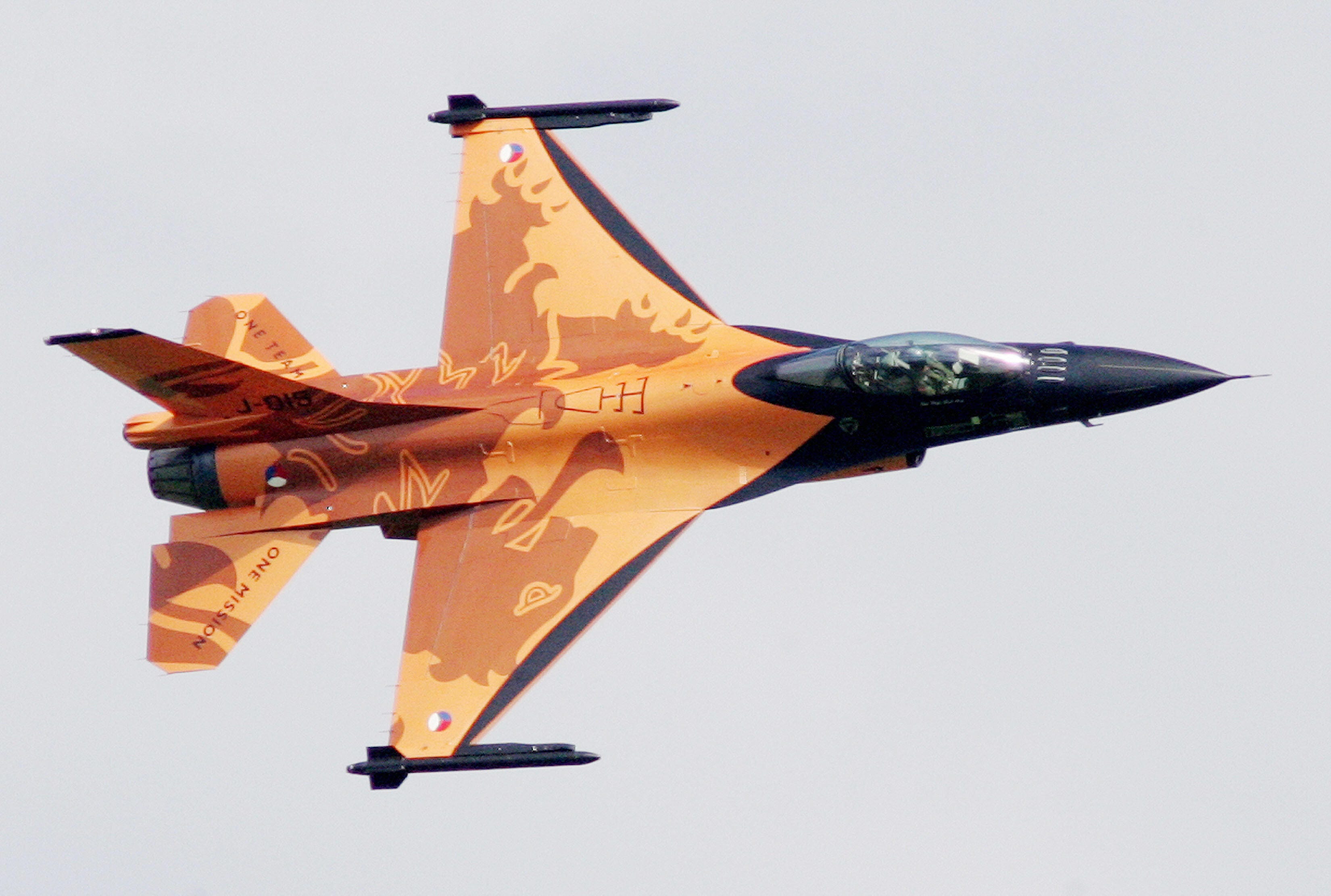 ein orangefarbener Kampfjet mitten im Flug