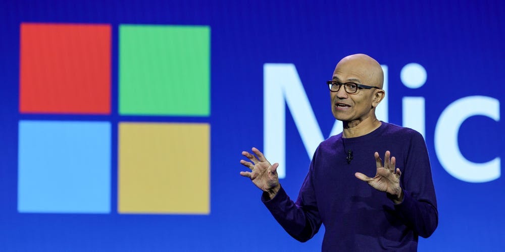 satya nadella vor einem Microsoft-Logo