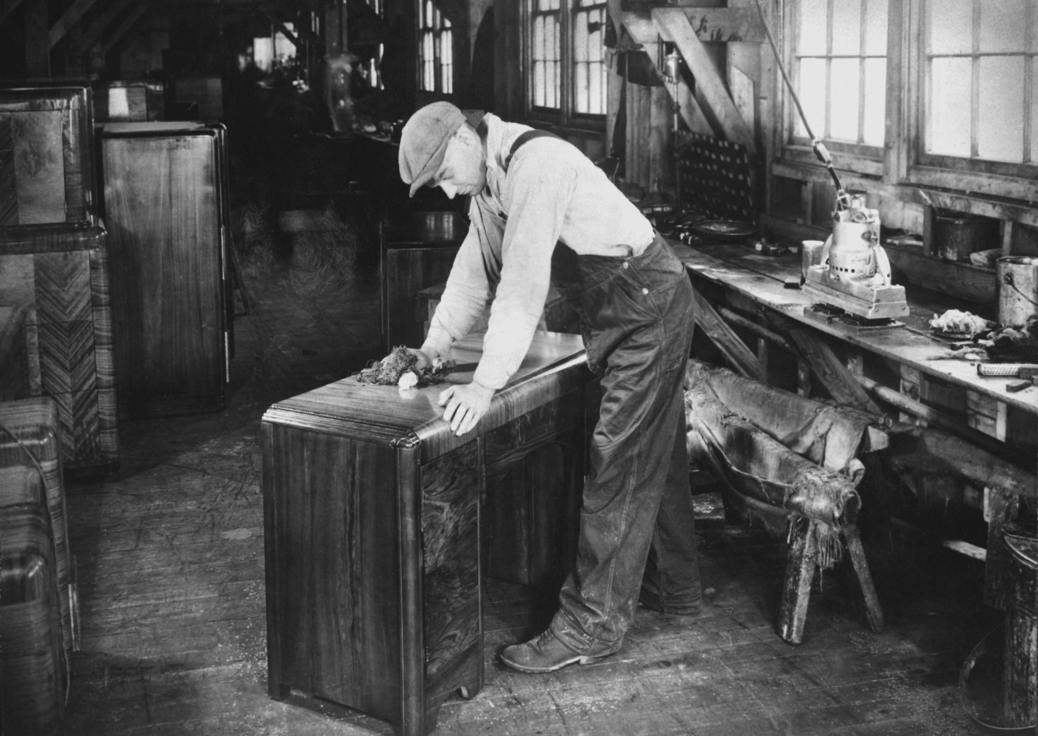 Ein Fabrikarbeiter poliert die Tischplatte in einer US-amerikanischen Möbelfabrik, um 1950.