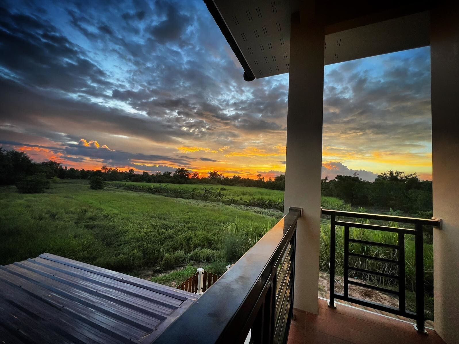 Ein Sonnenuntergang vom Balkon eines Hauses aus gesehen.