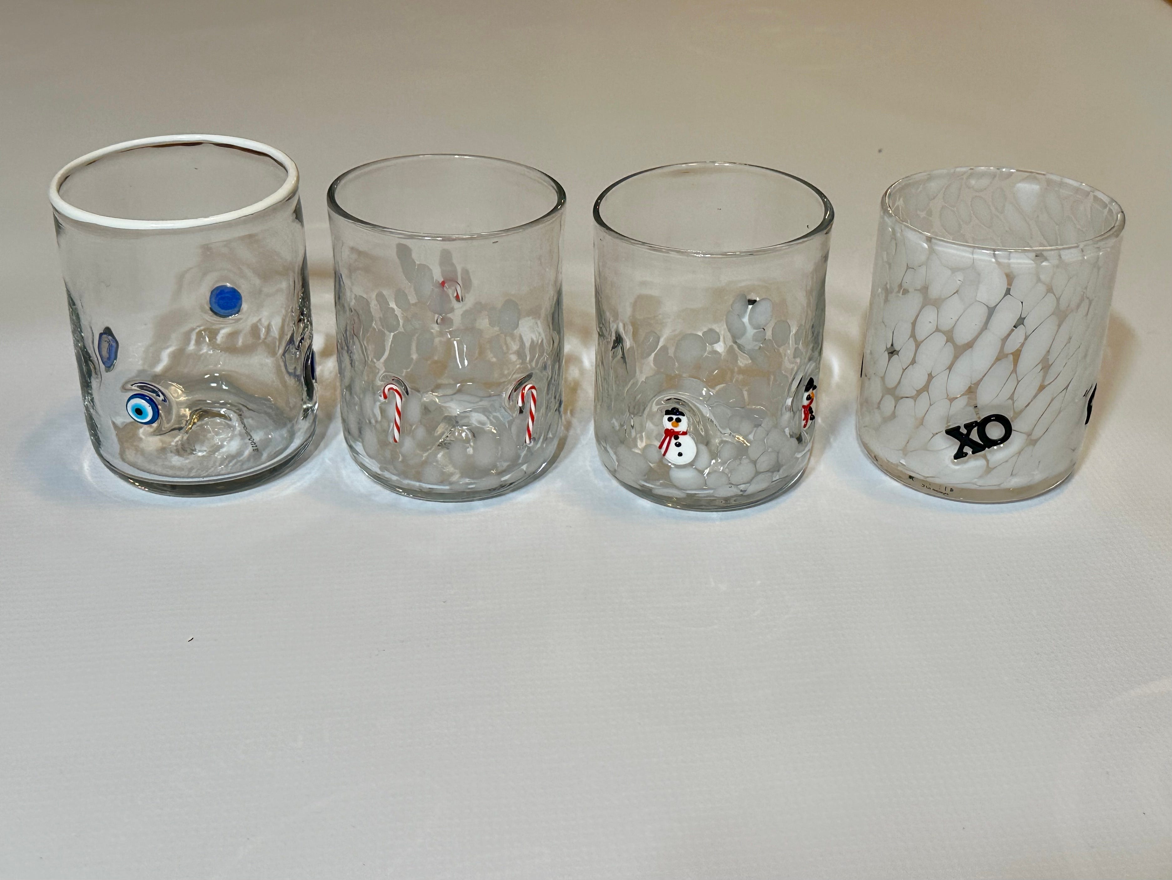 Klare Gläser mit verschiedenen Mustern, darunter böser Blick, Zuckerstange, Schneemänner und „XO“-Muster