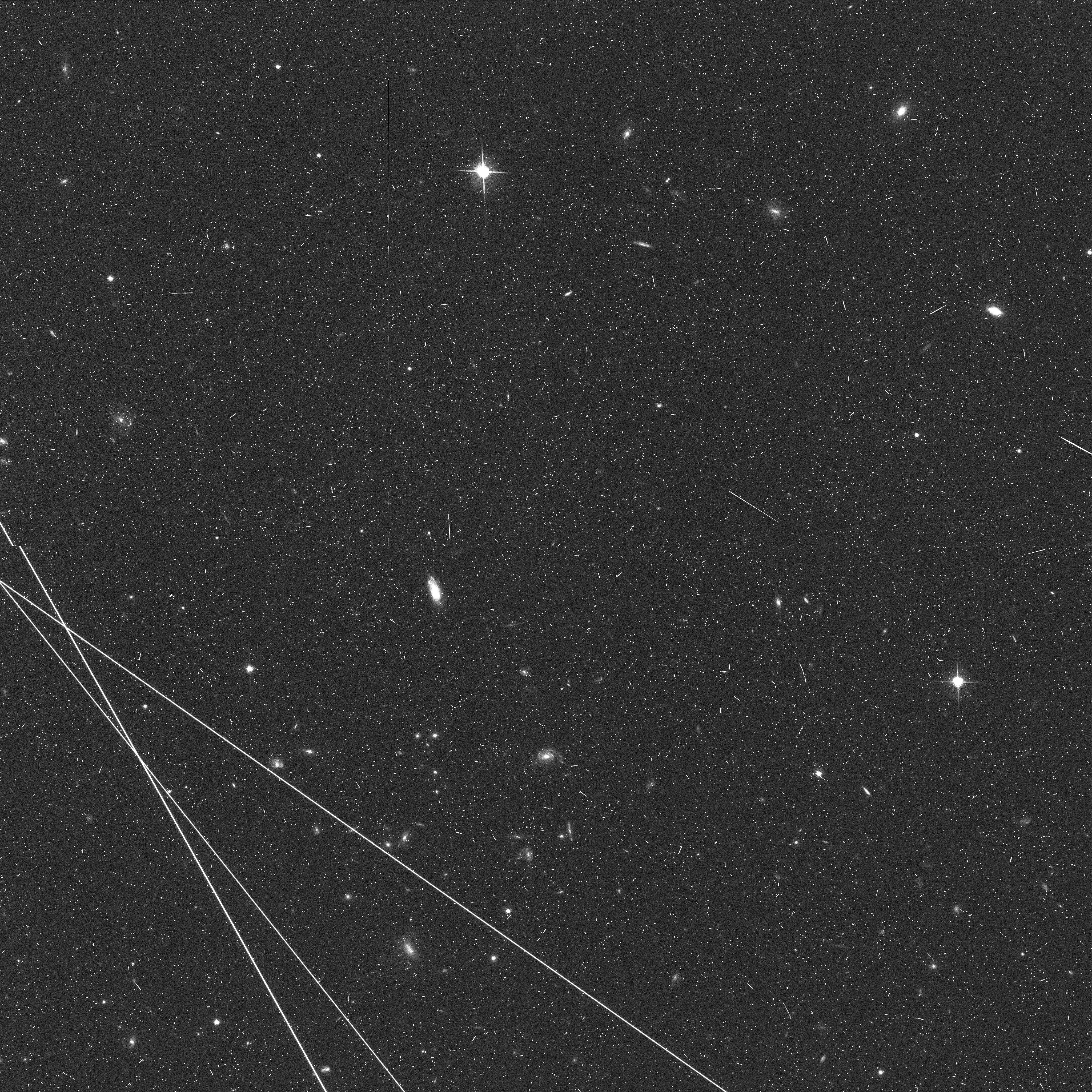 Drei weiße Satellitenlinien ziehen sich über das Schwarz-Weiß-Bild des Sternenuniversums