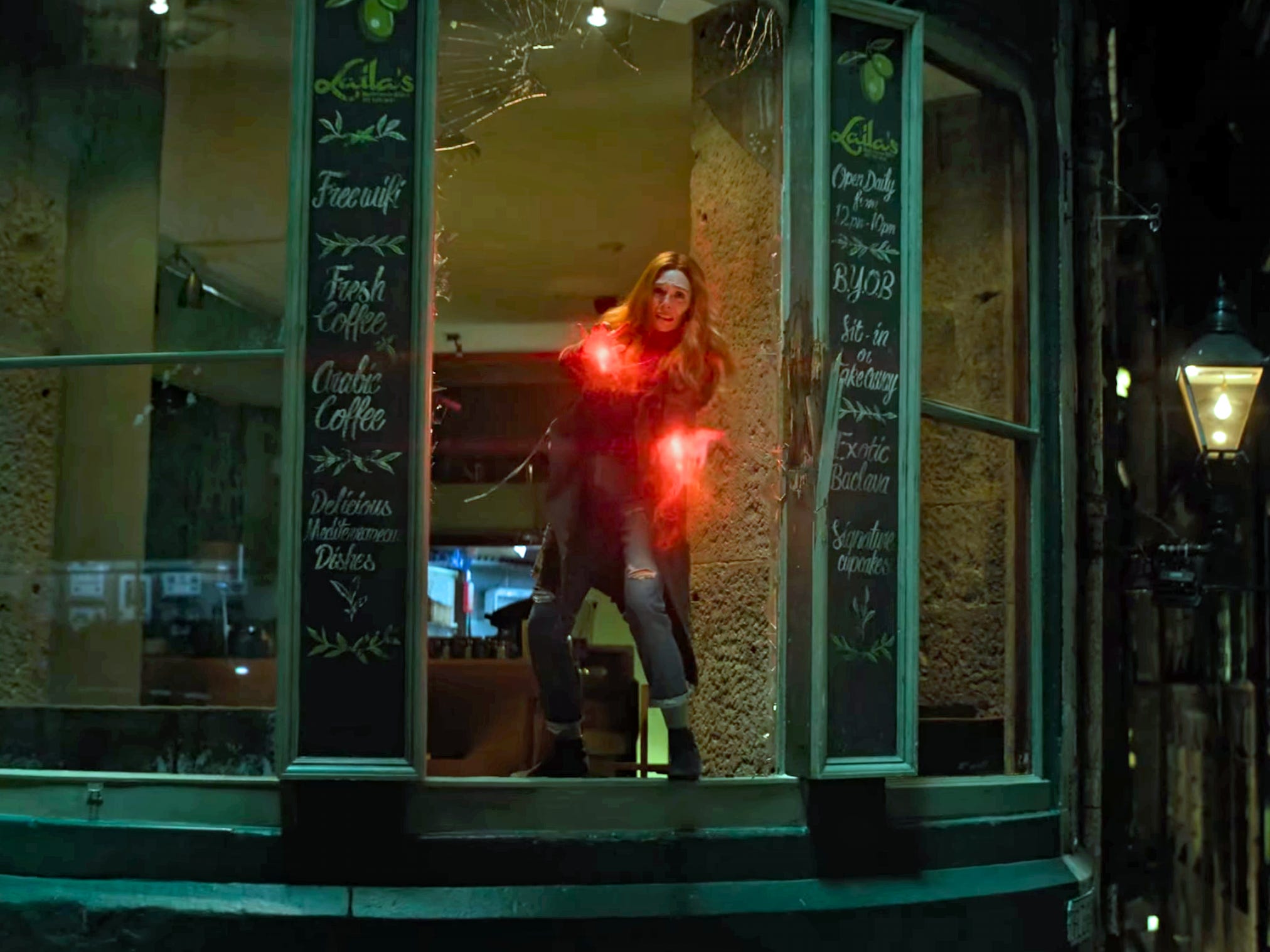 Wanda steht im Fenster eines Cafés mit rot leuchtenden Händen in „Avengers Infinity Wars“.