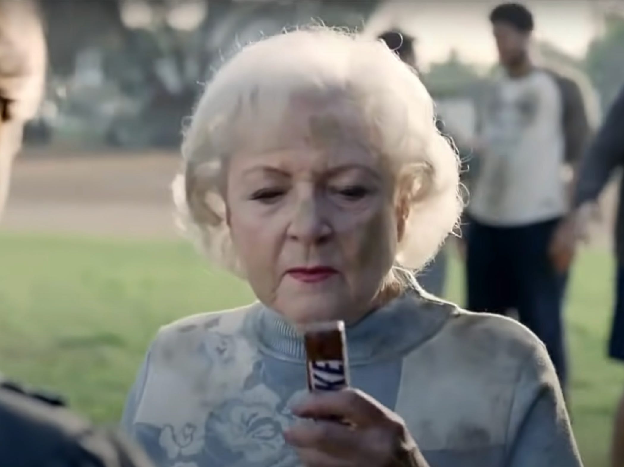 Betty White hält einen Snickers-Riegel in der Hand.