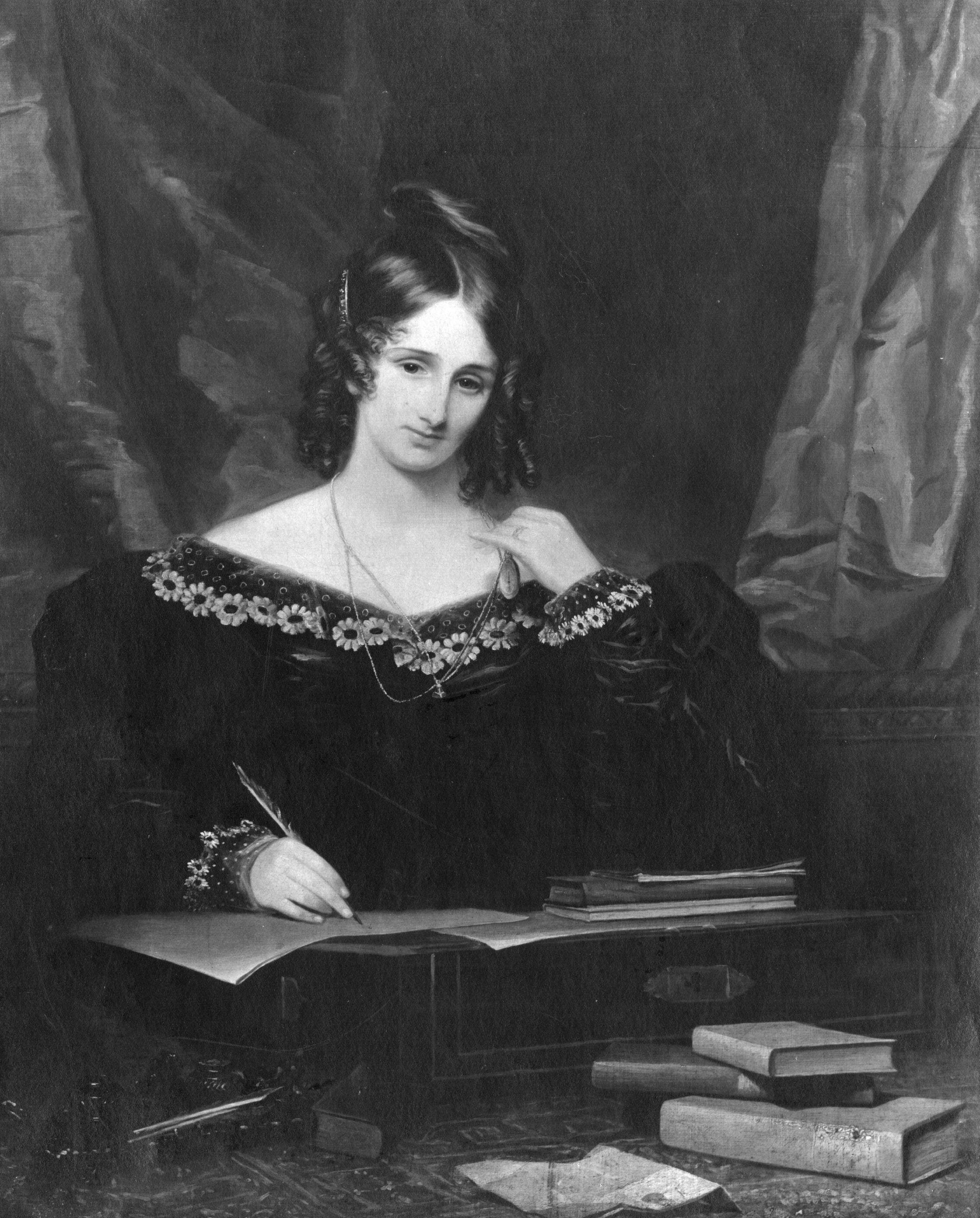 Ein Schwarz-Weiß-Bild von Mary Shelley, die ein dunkles Kleid trägt und schreibt und von Büchern umgeben ist