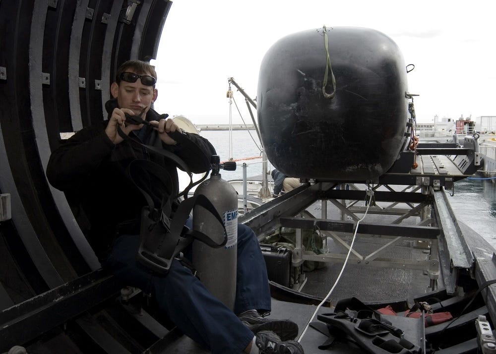 Ein Marinetaucher sitzt in einem trockenen Deckschutz an Bord eines Raketen-U-Bootes