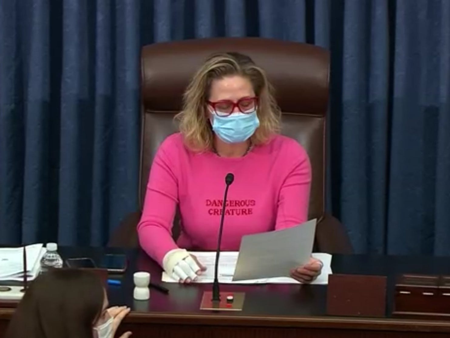 Senatorin Kyrsten Sinema trägt einen rosa Pullover mit der Aufschrift „Gefährliche Kreatur“.