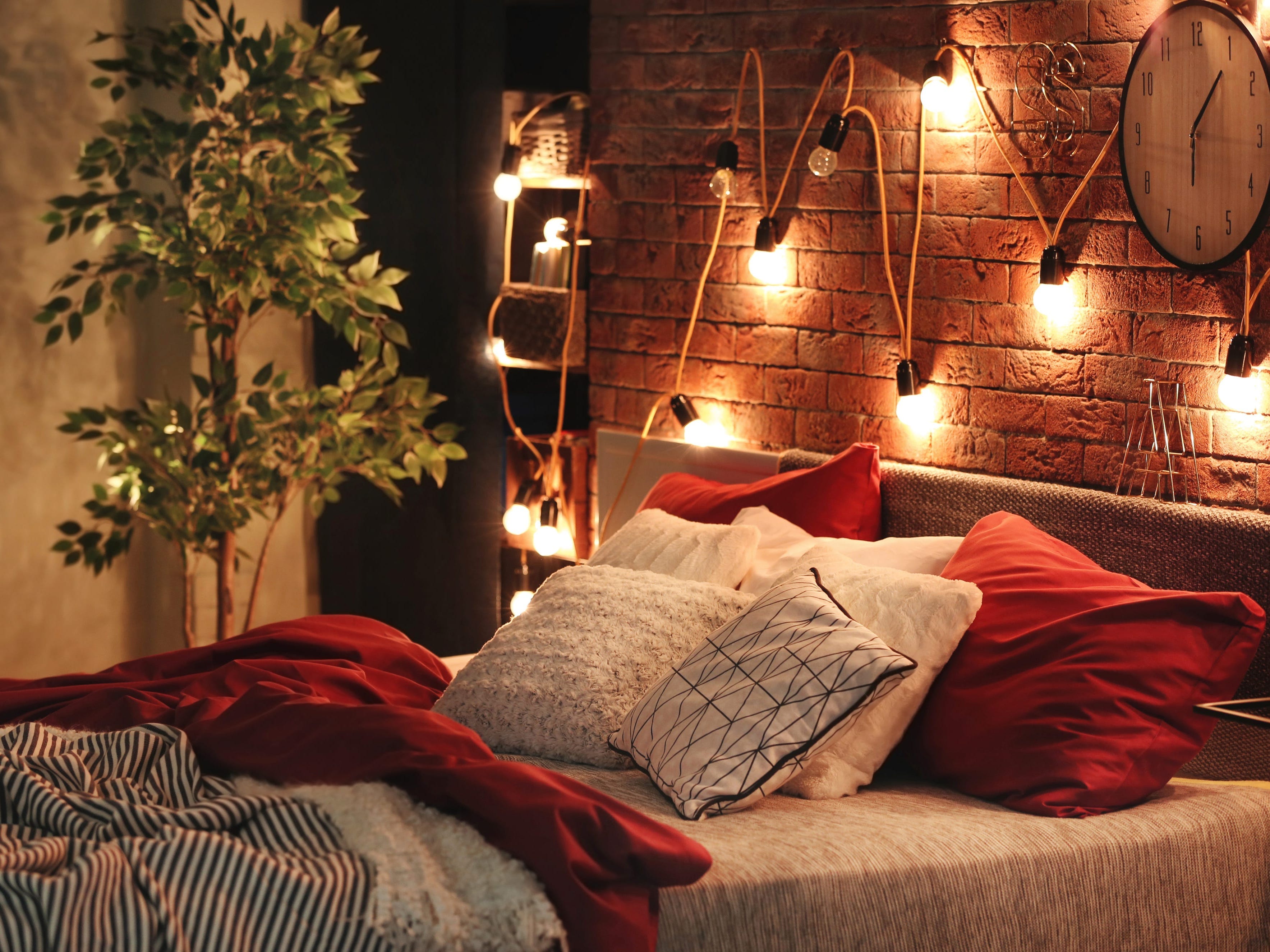 Schlafzimmer mit Glühbirnen und roter Bettwäsche dekoriert