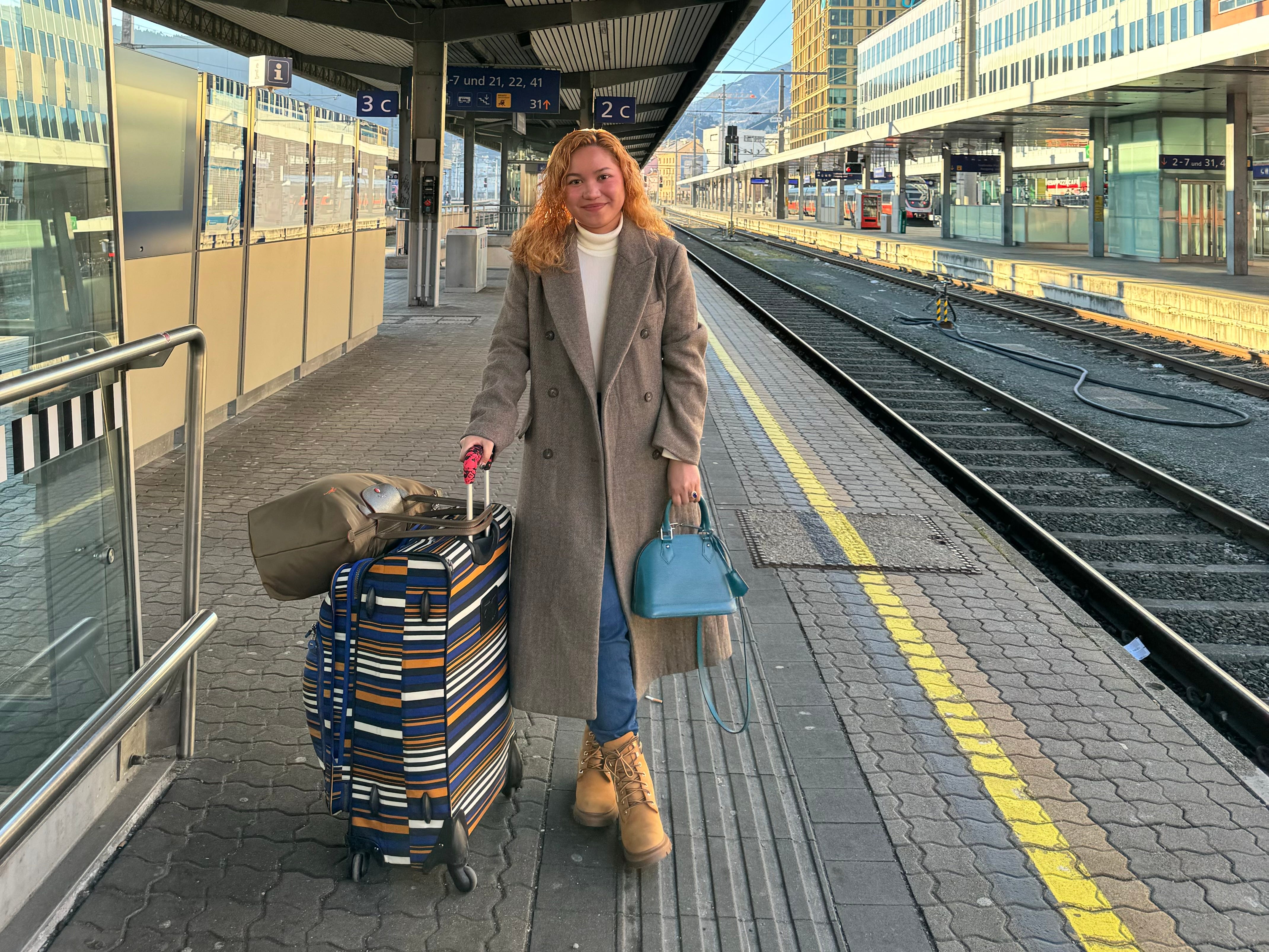 Frau mit großem Koffer auf Bahngleis