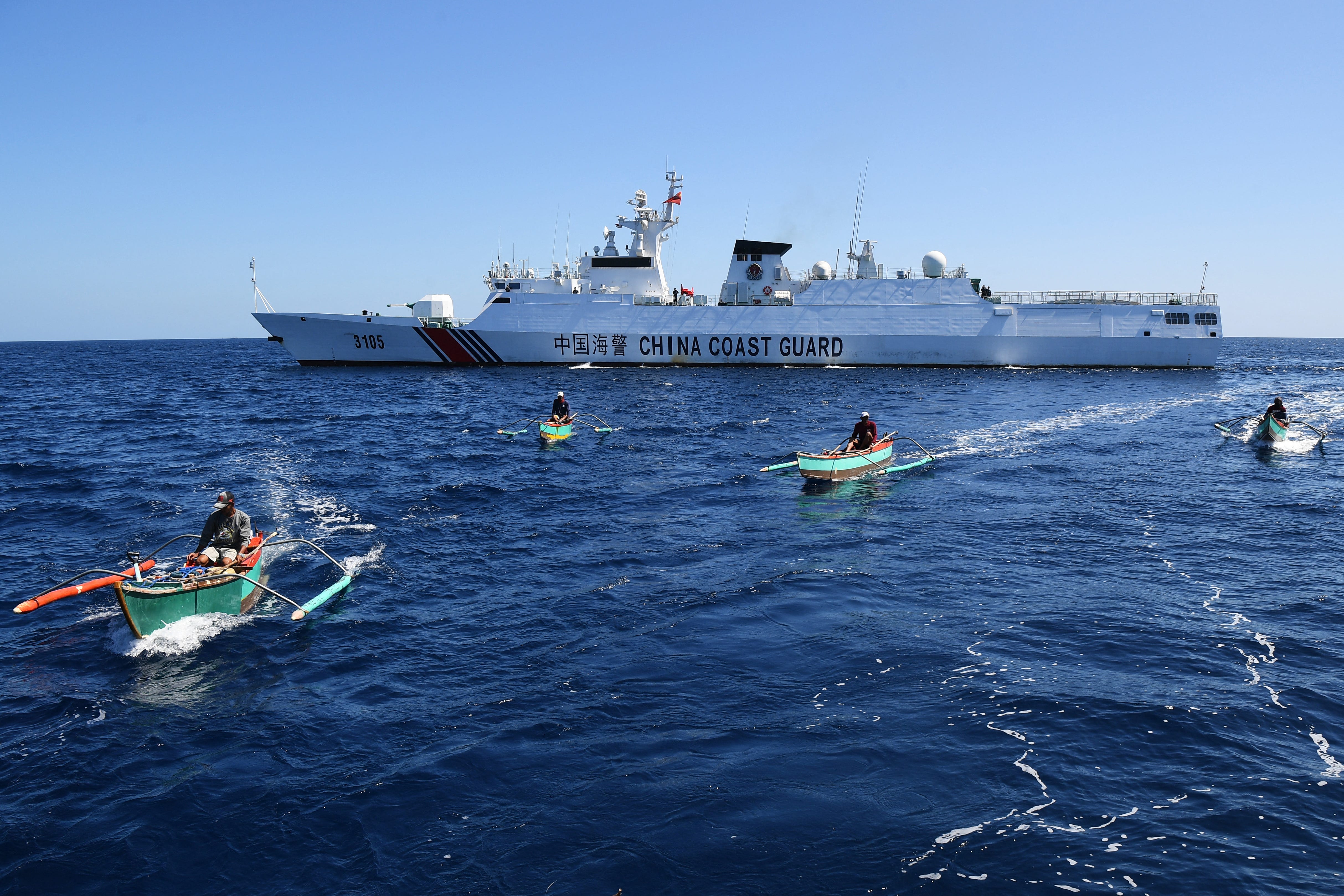 Philippinische Fischer an Bord ihrer Holzboote segeln an einem Schiff der chinesischen Küstenwache in der Nähe des von China kontrollierten Scarborough Shoal in umstrittenen Gewässern des Südchinesischen Meeres vorbei.