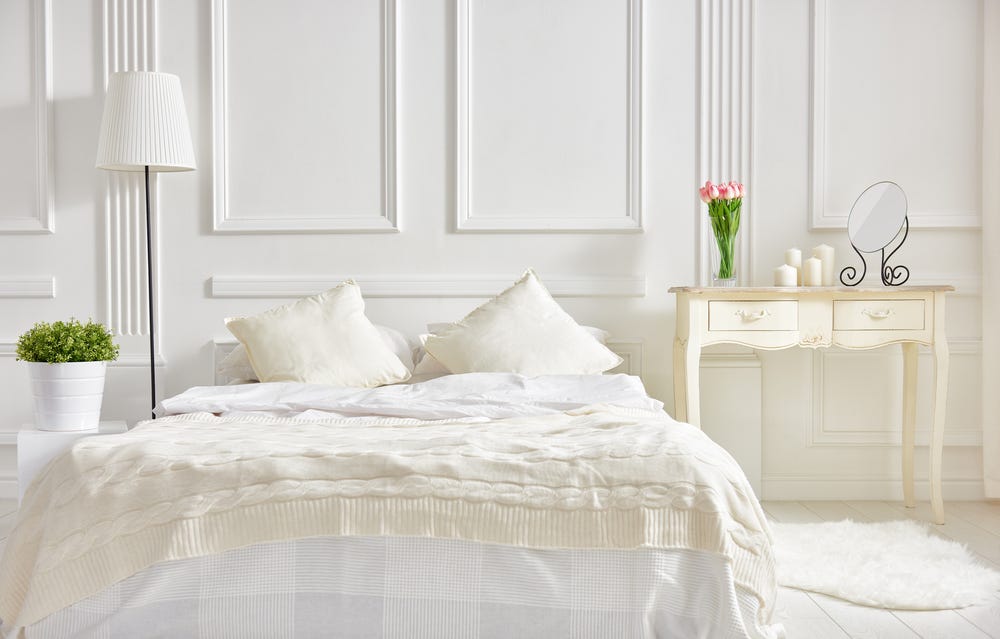 Weißes Schlafzimmer mit beigen Decken