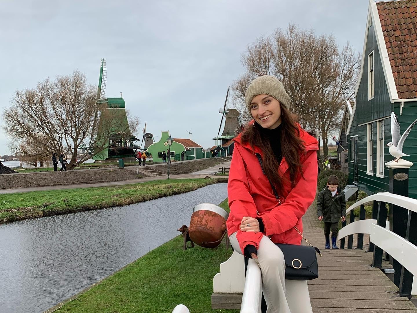Mädchen in roter Jacke posiert in der Nähe holländischer Windmühlen.