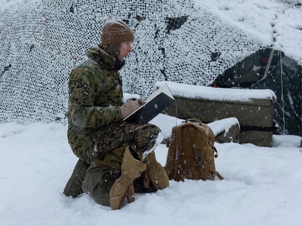 Ein Kampfkünstler kniet im Schnee, während er Marineinfanteristen beim Training bei kaltem Wetter illustriert