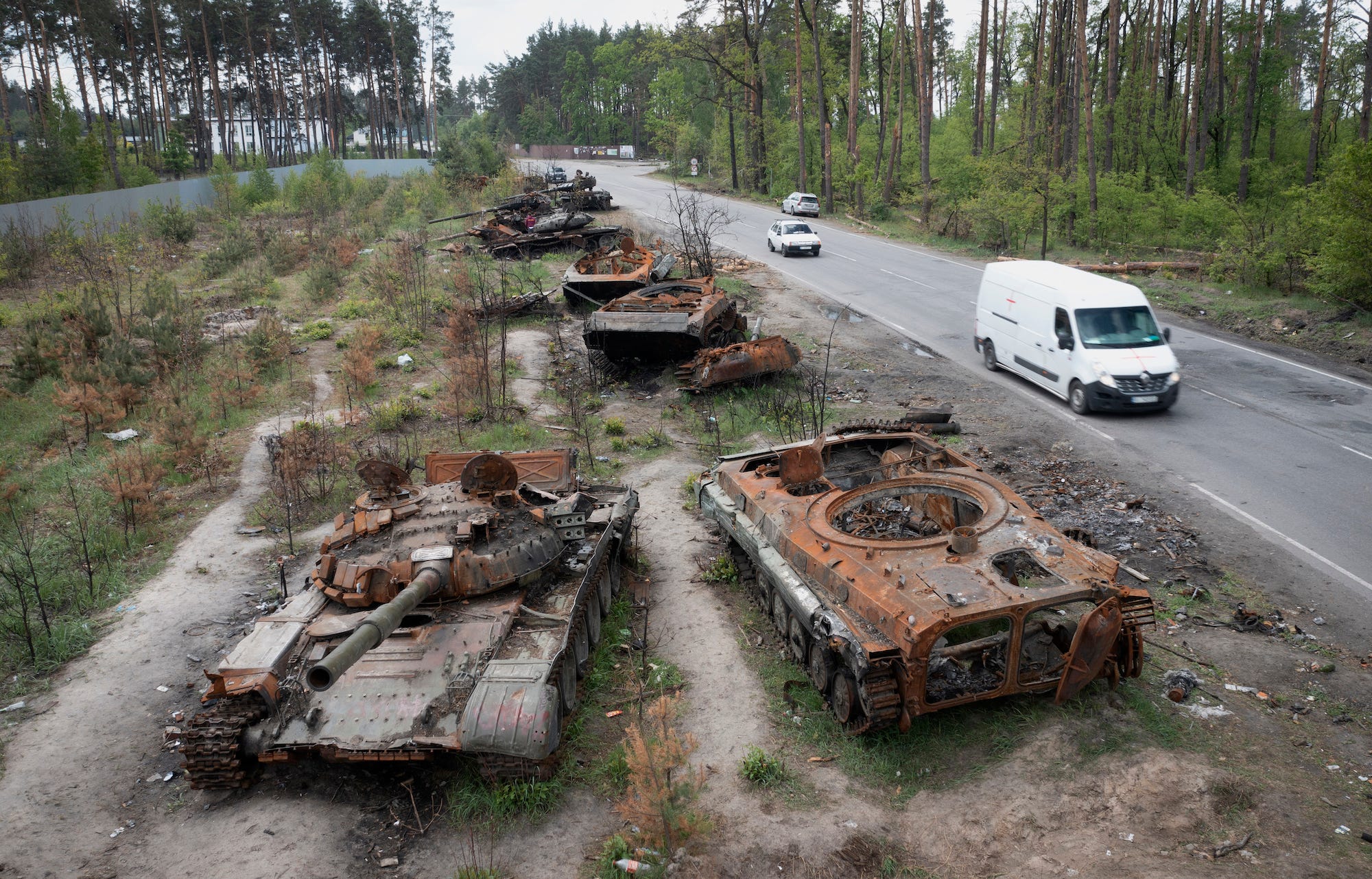 Autos fahren neben einer Straße an zerstörten russischen Panzern vorbei