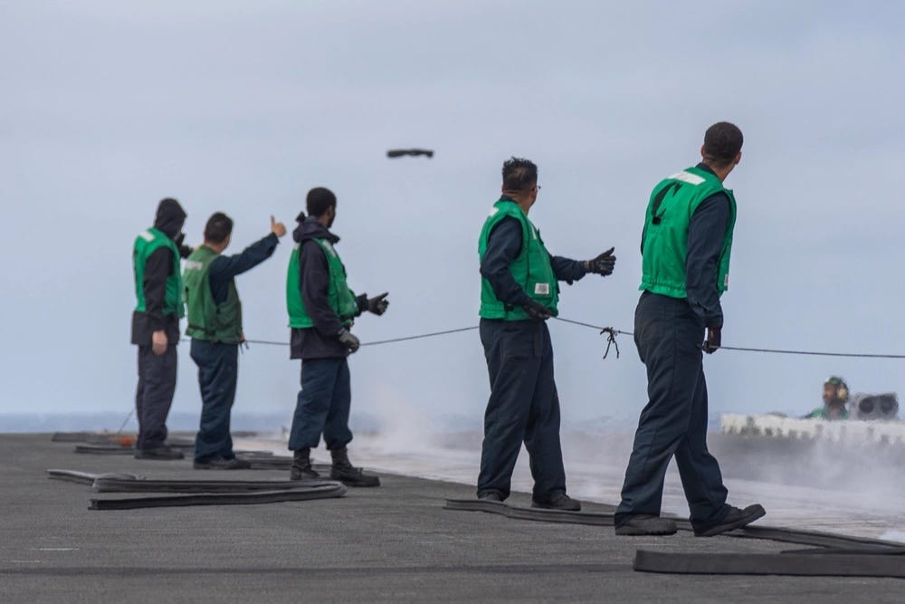 Matrosen beobachten den Start von Stiefeln während eines „Boot-Shootings“ auf dem Flugdeck