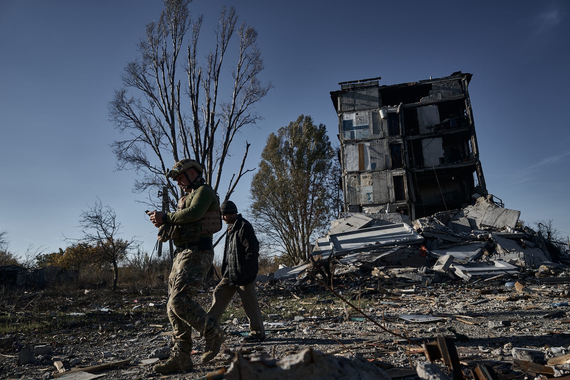 Ein ukrainischer Soldat der Spezialeinheit „Weißer Engel“, ein Einheimischer und ein heruntergekommenes Haus im Hintergrund