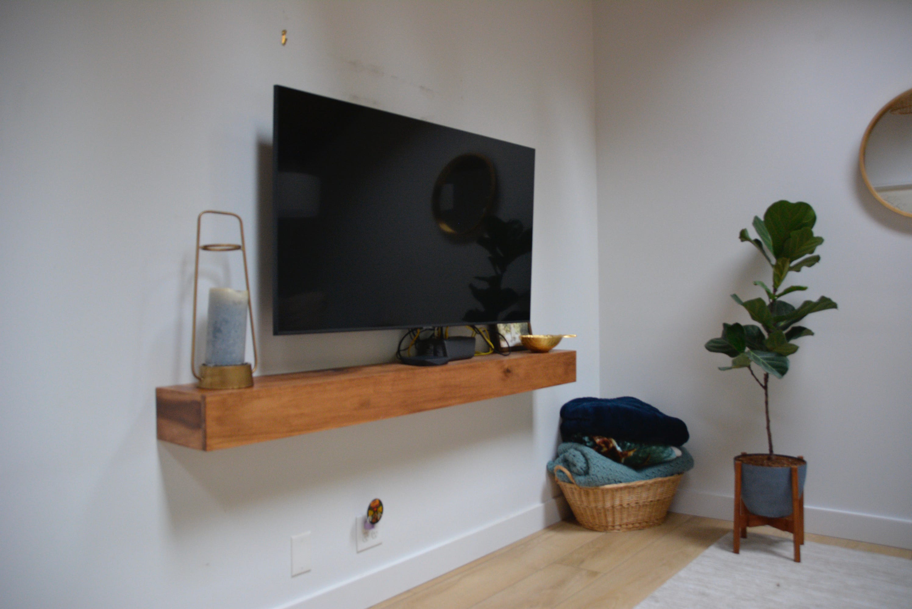 Fernseher über einer Holzleiste an einer weißen Wand