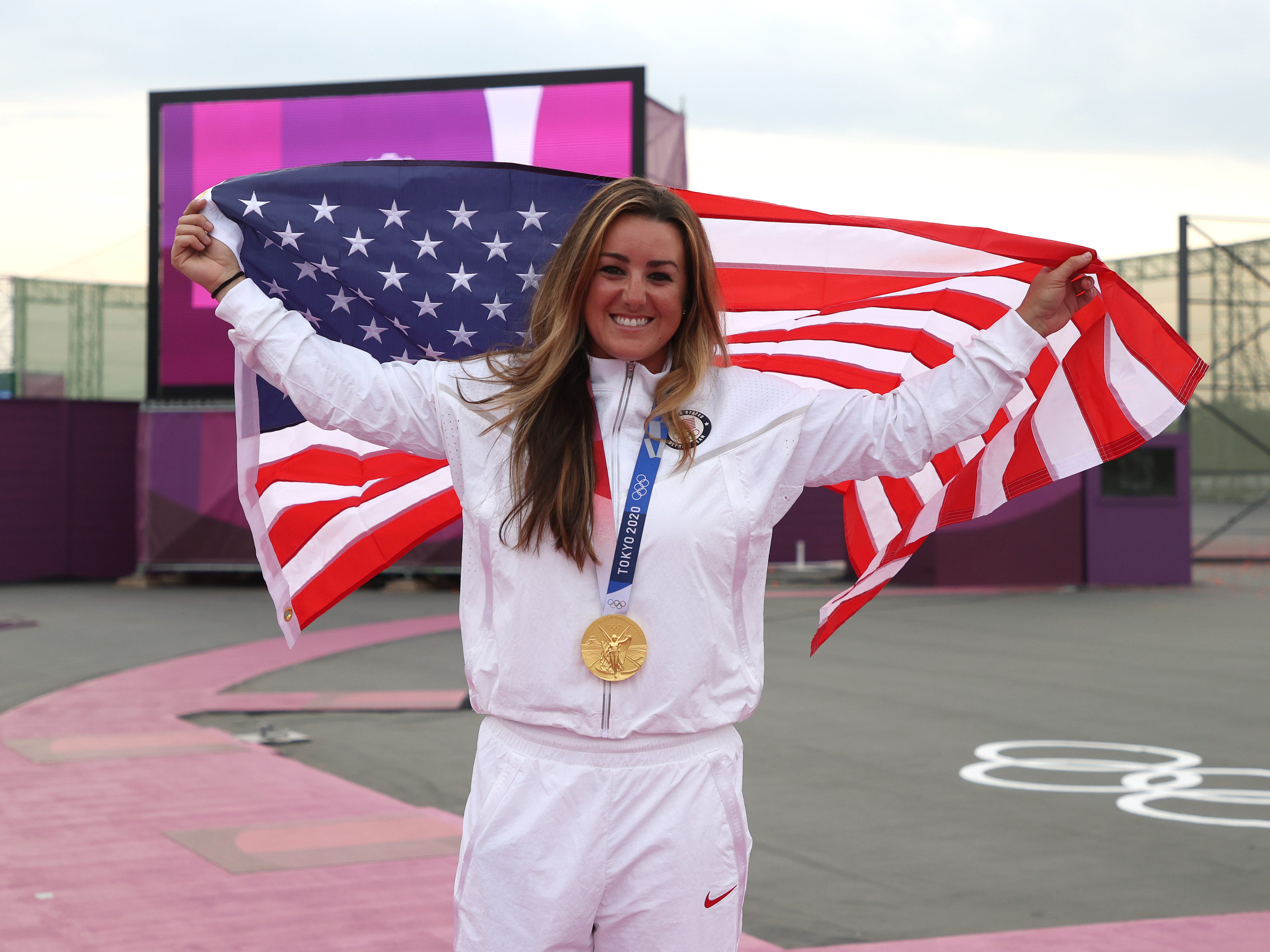Amber English hisst die amerikanische Flagge, während sie bei den Olympischen Spielen in Tokio ihre Goldmedaille trägt.