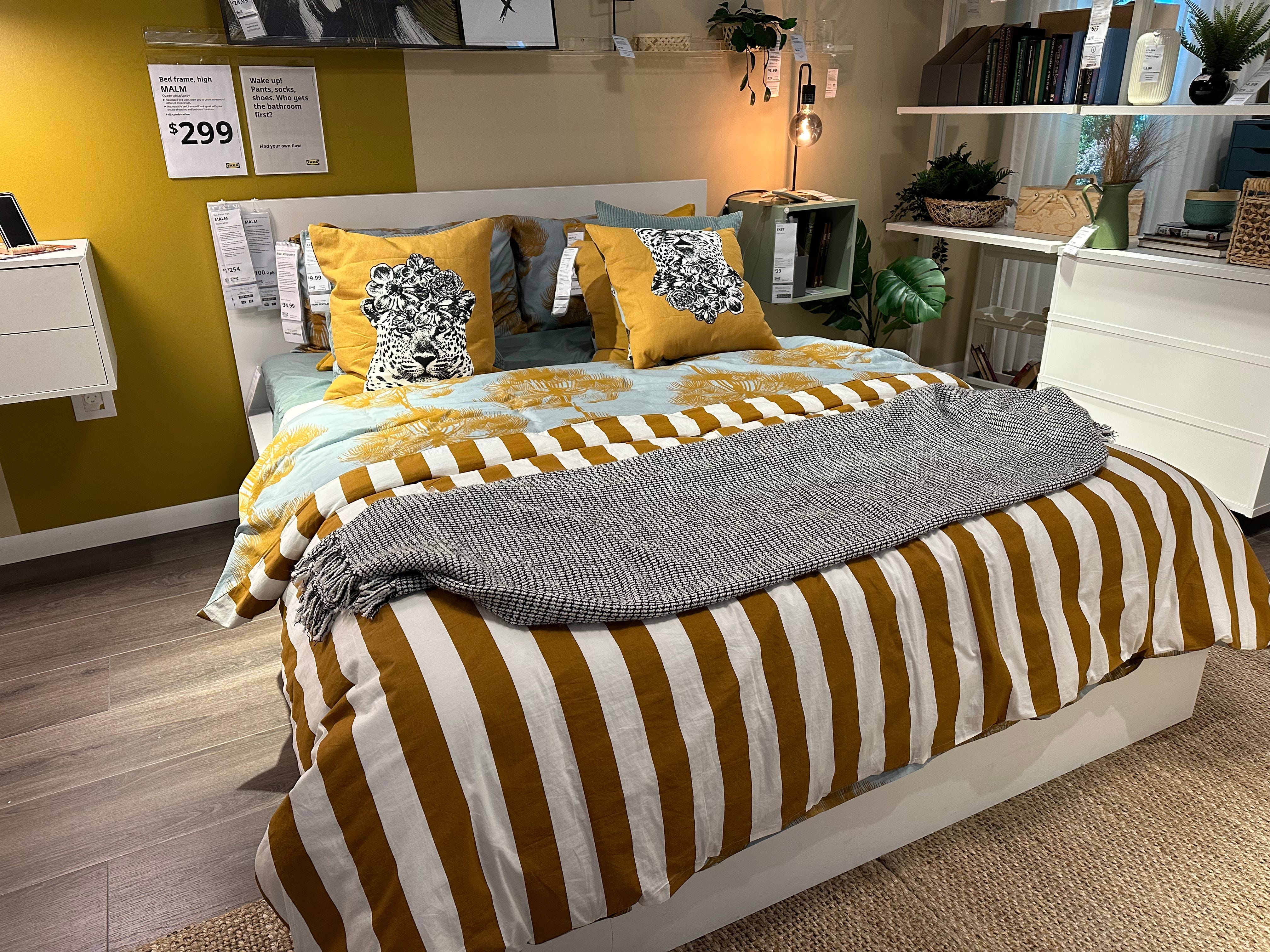 Bett mit gestreifter, gelber und blauer Bettwäsche bei Ikea