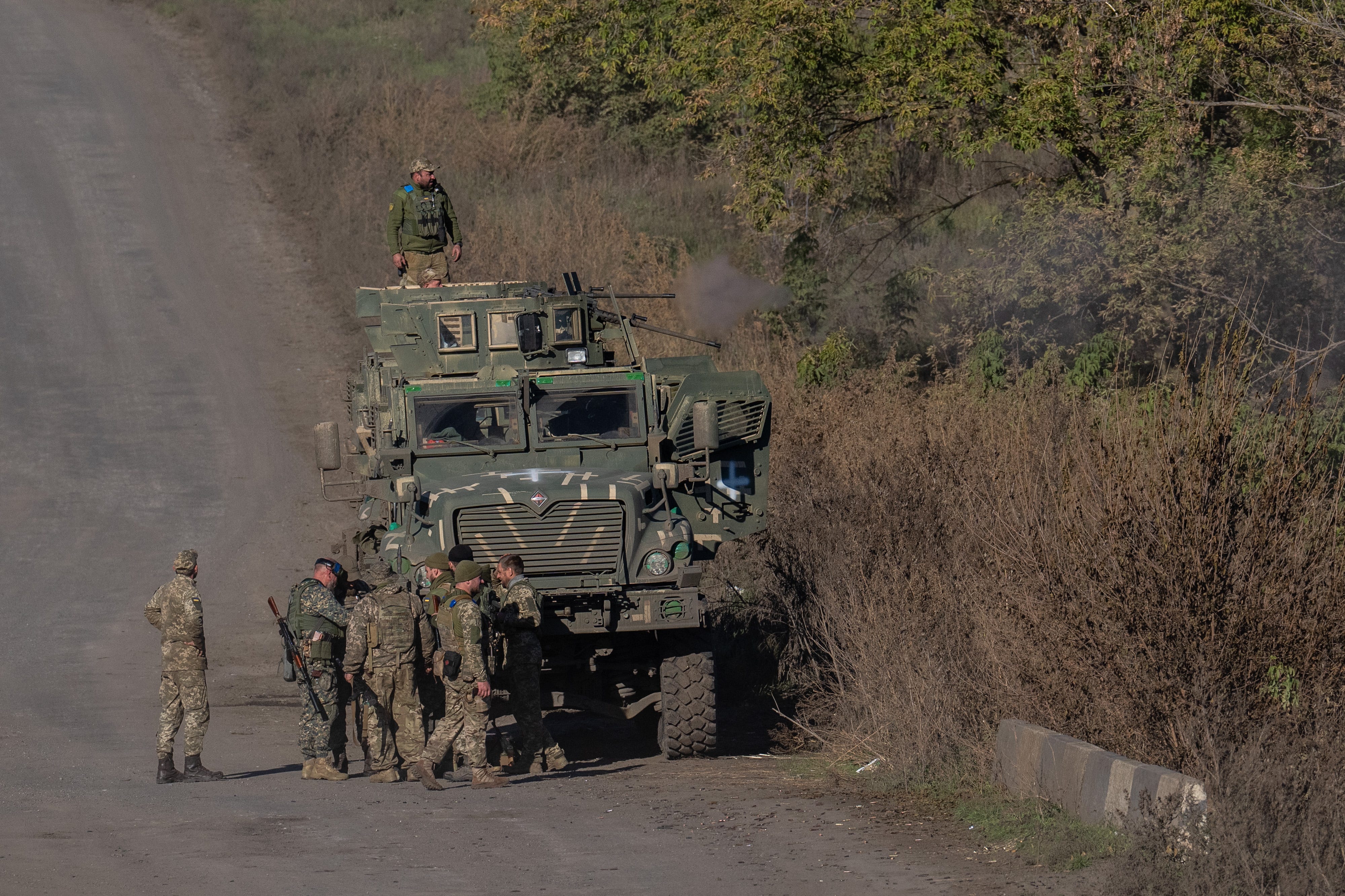 Soldaten in Tarnung in der Nähe eines gepanzerten Fahrzeugs auf einer unbefestigten Straße