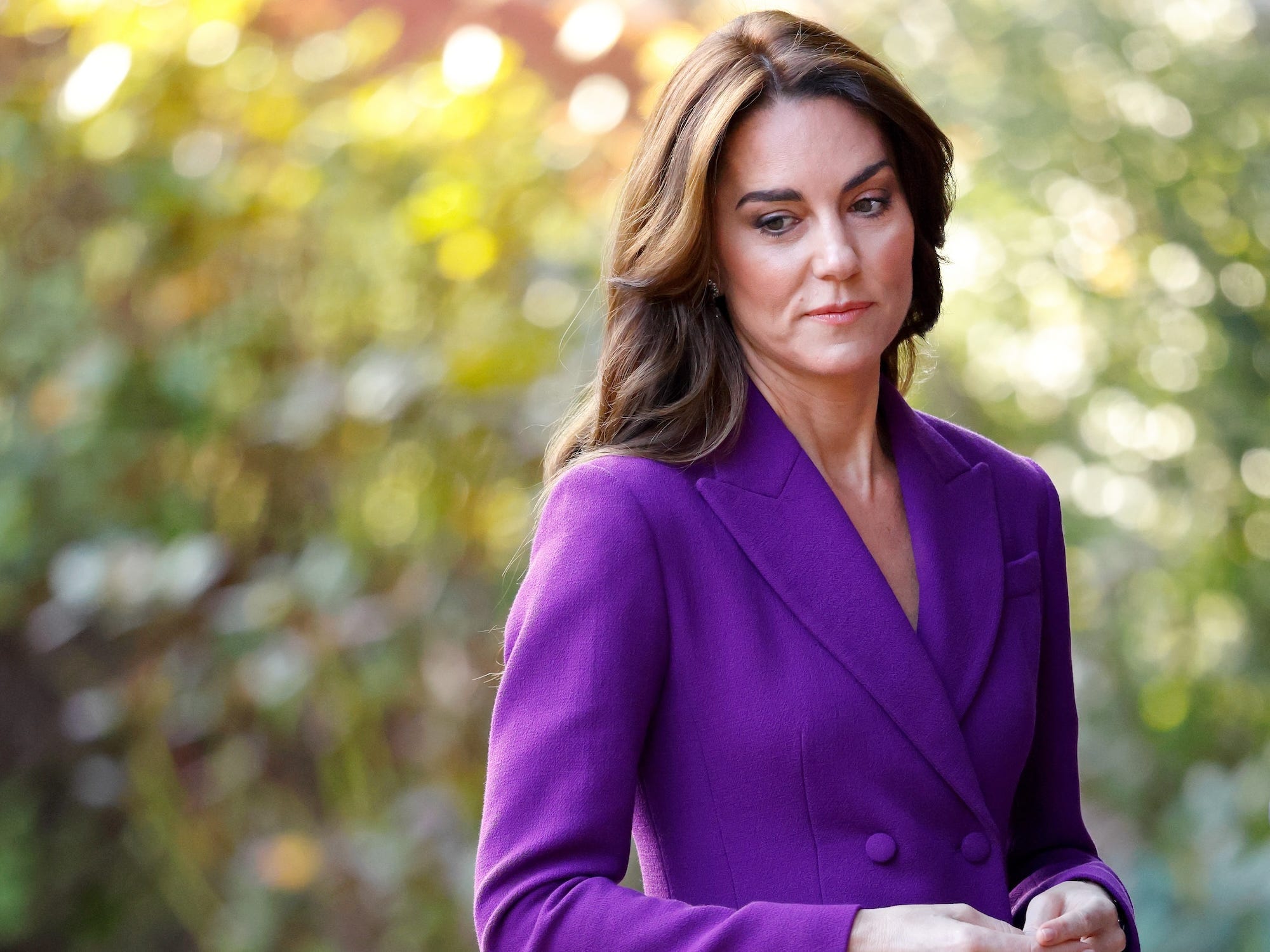 Kate Middleton blickt in einem lila Anzug nach unten.