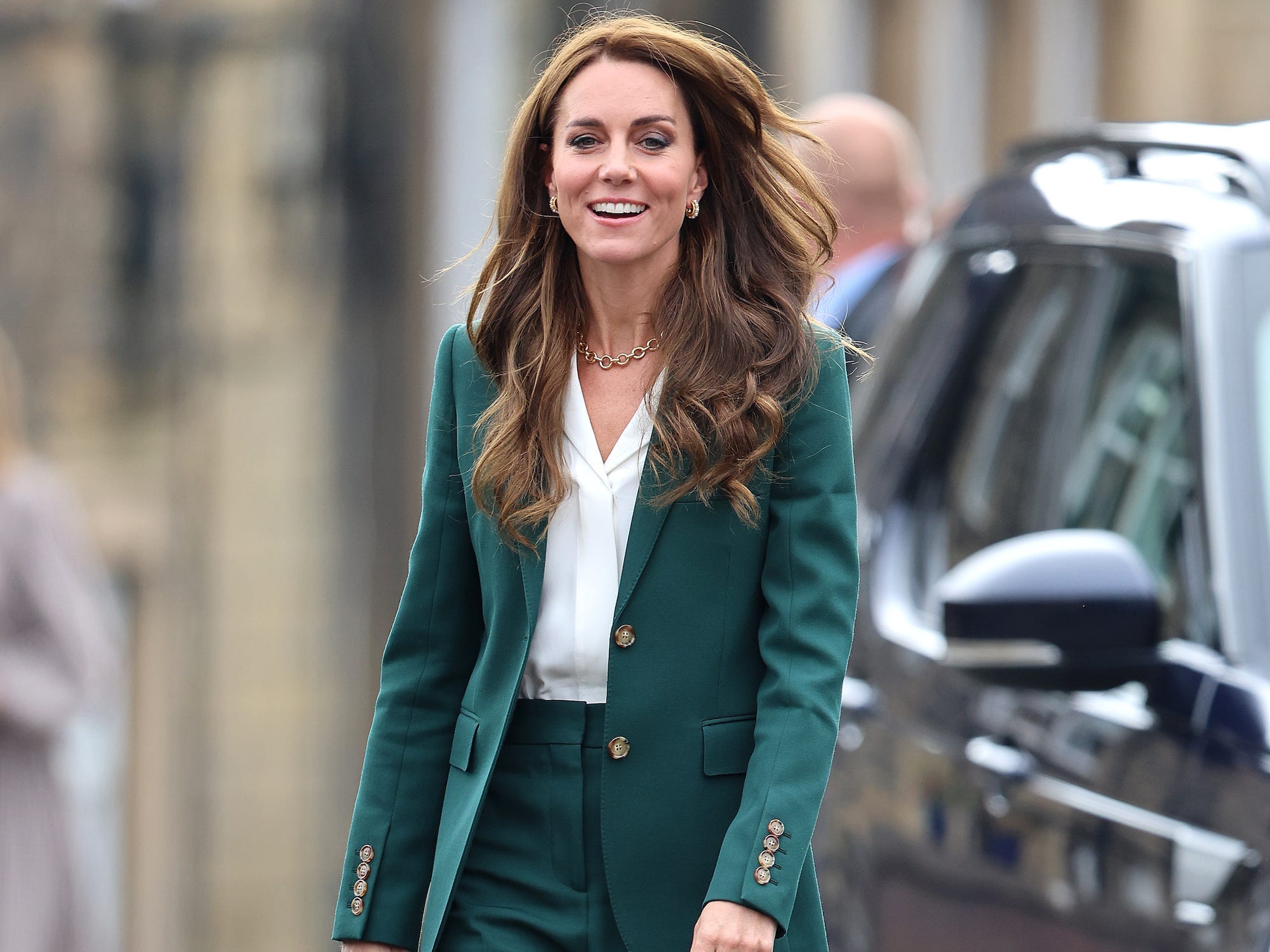 Kate Middleton läuft in einem grünen Anzug neben einem Auto.