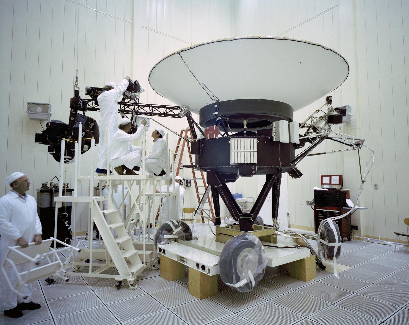 Mehrere Personen in weißen Overalls arbeiten in einem Lagerhaus an der Raumsonde Voyager 2