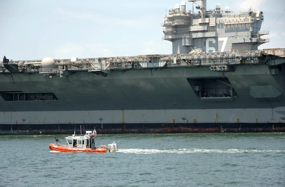 Ein sicheres Boot unterhält eine Sicherheitszone rund um die USS John F. Kennedy