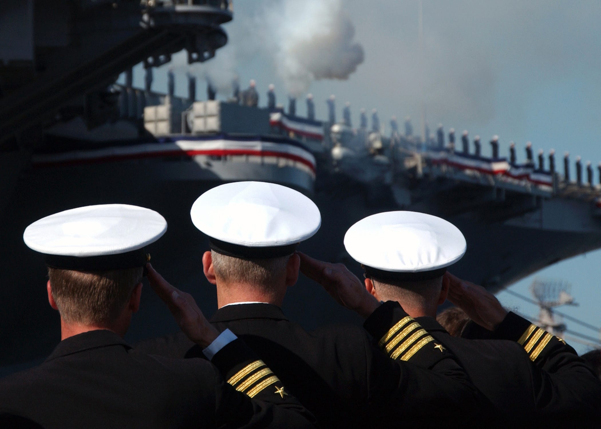 Drei Offiziere salutieren bei der Stilllegungszeremonie der USS John F. Kennedy