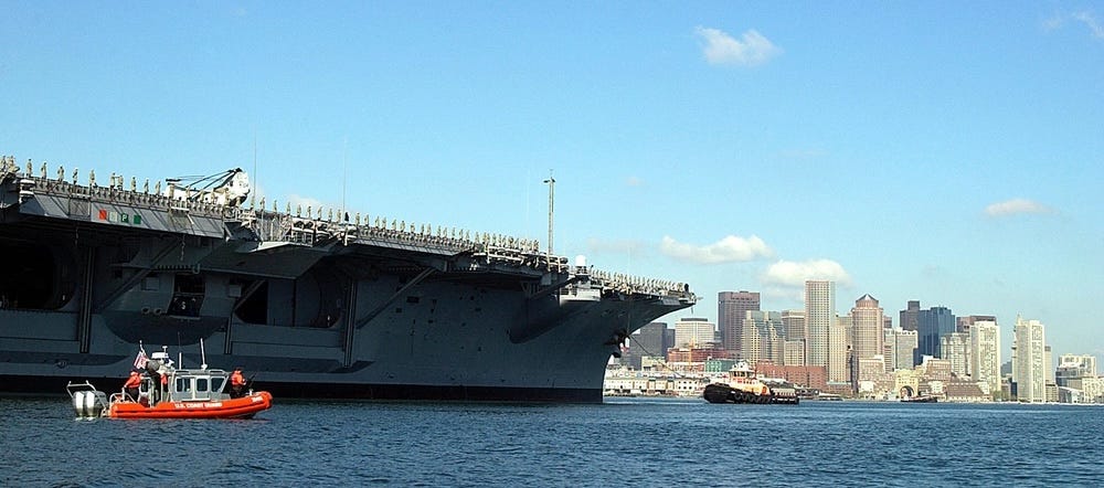 ein 25-Fuß-Boot der Defender-Klasse und die USS John F. Kennedy im Hafen von Boston