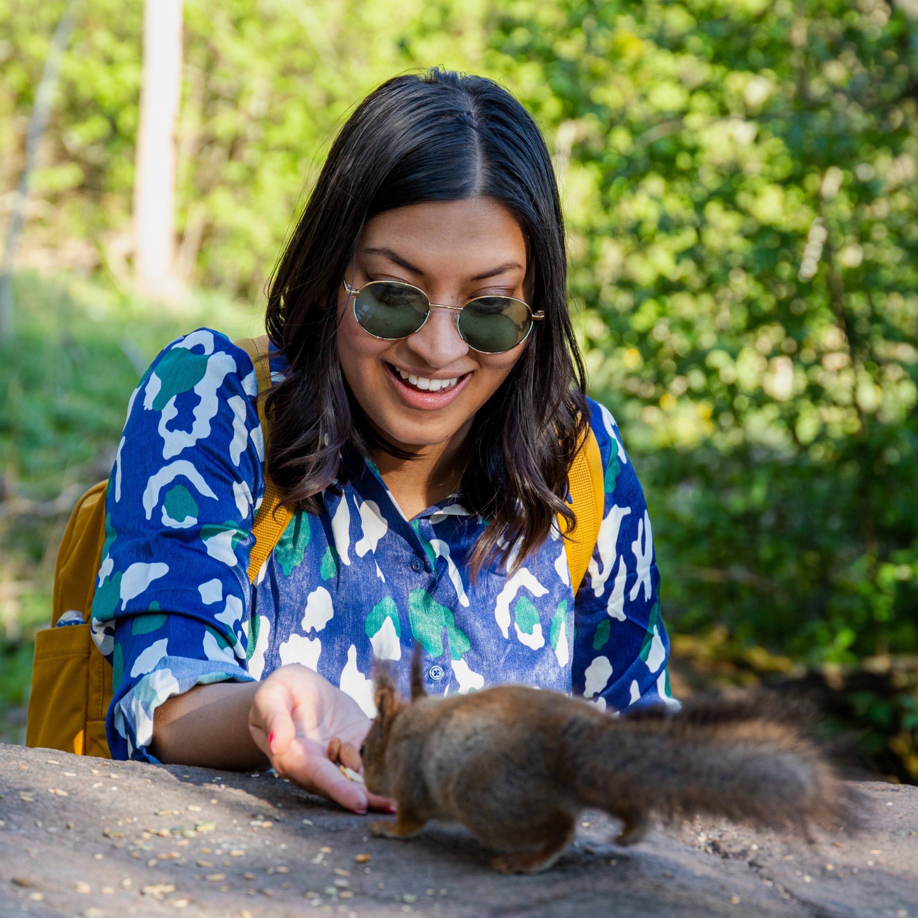 Megha Goswami füttert draußen ein Eichhörnchen.