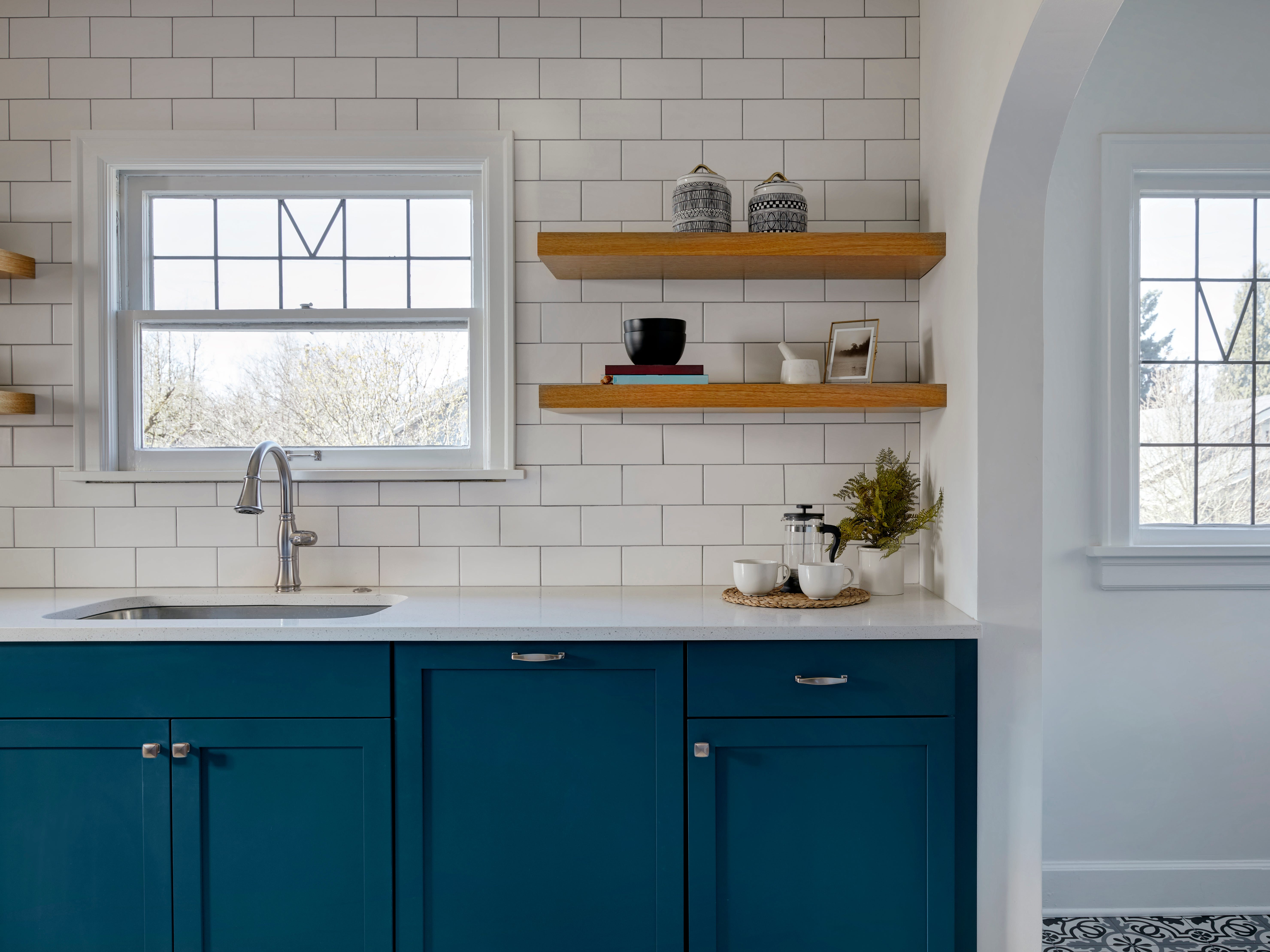 Blau lackierte Schränke in einer Küche mit weißer Theke und Rückwand