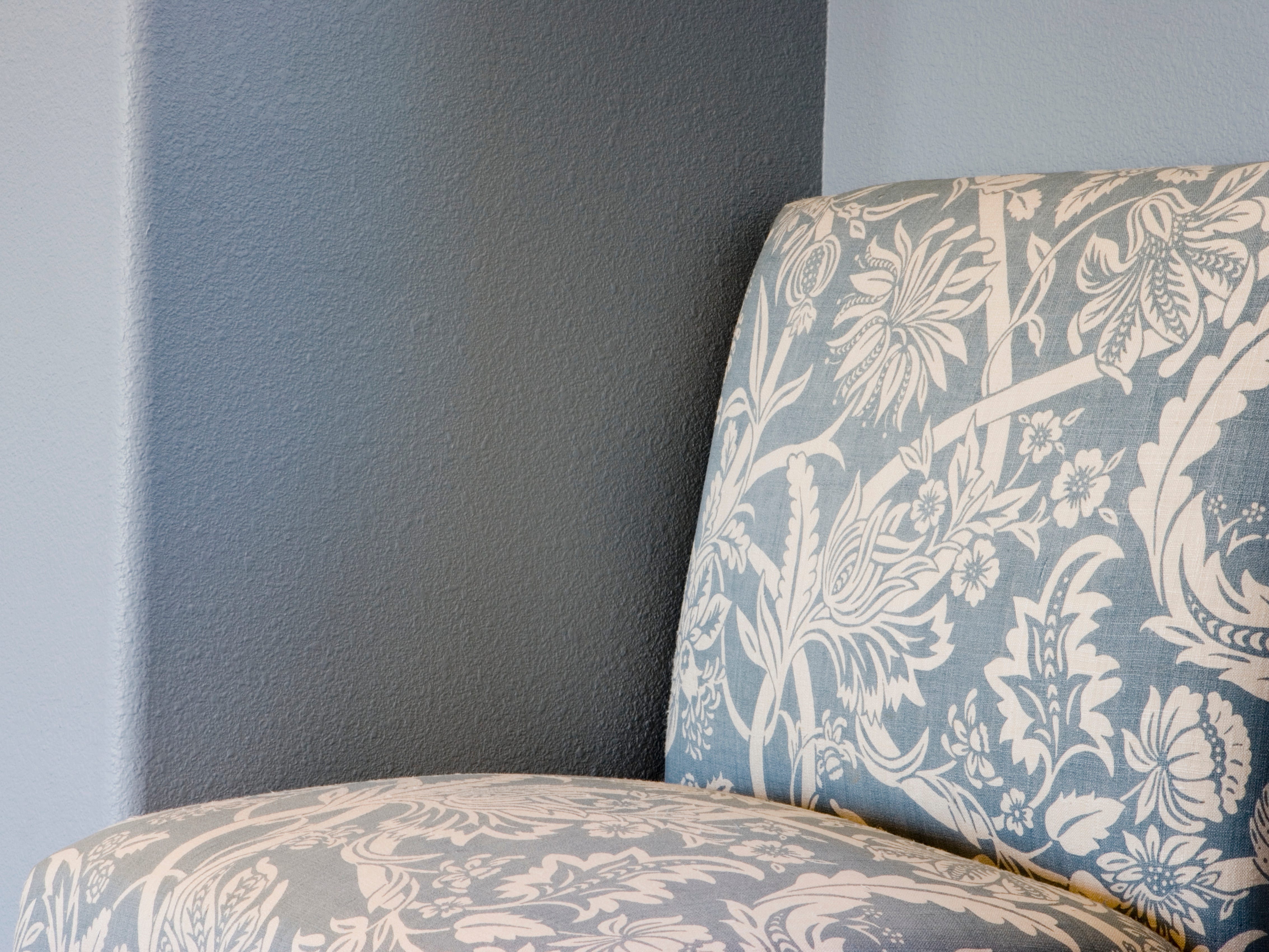 Blau-weiß gepolsterter Stuhl vor grauer Wand