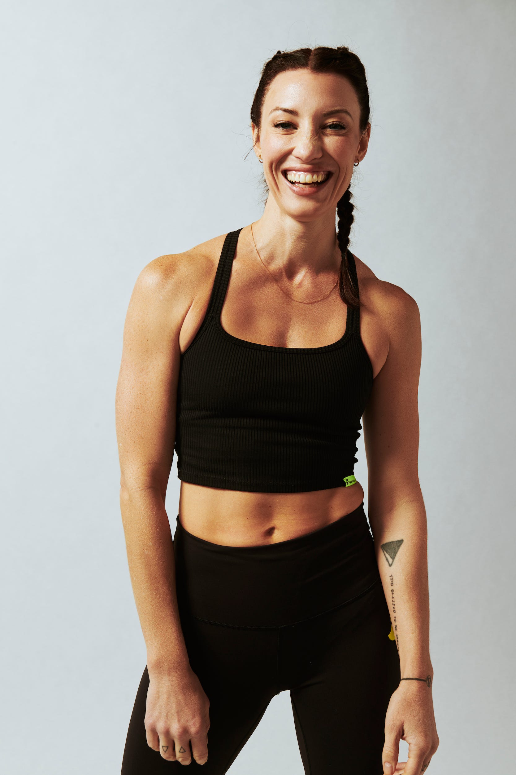 Eine Frau lächelt, während sie ein kurzes Trainingsoberteil und Leggings trägt