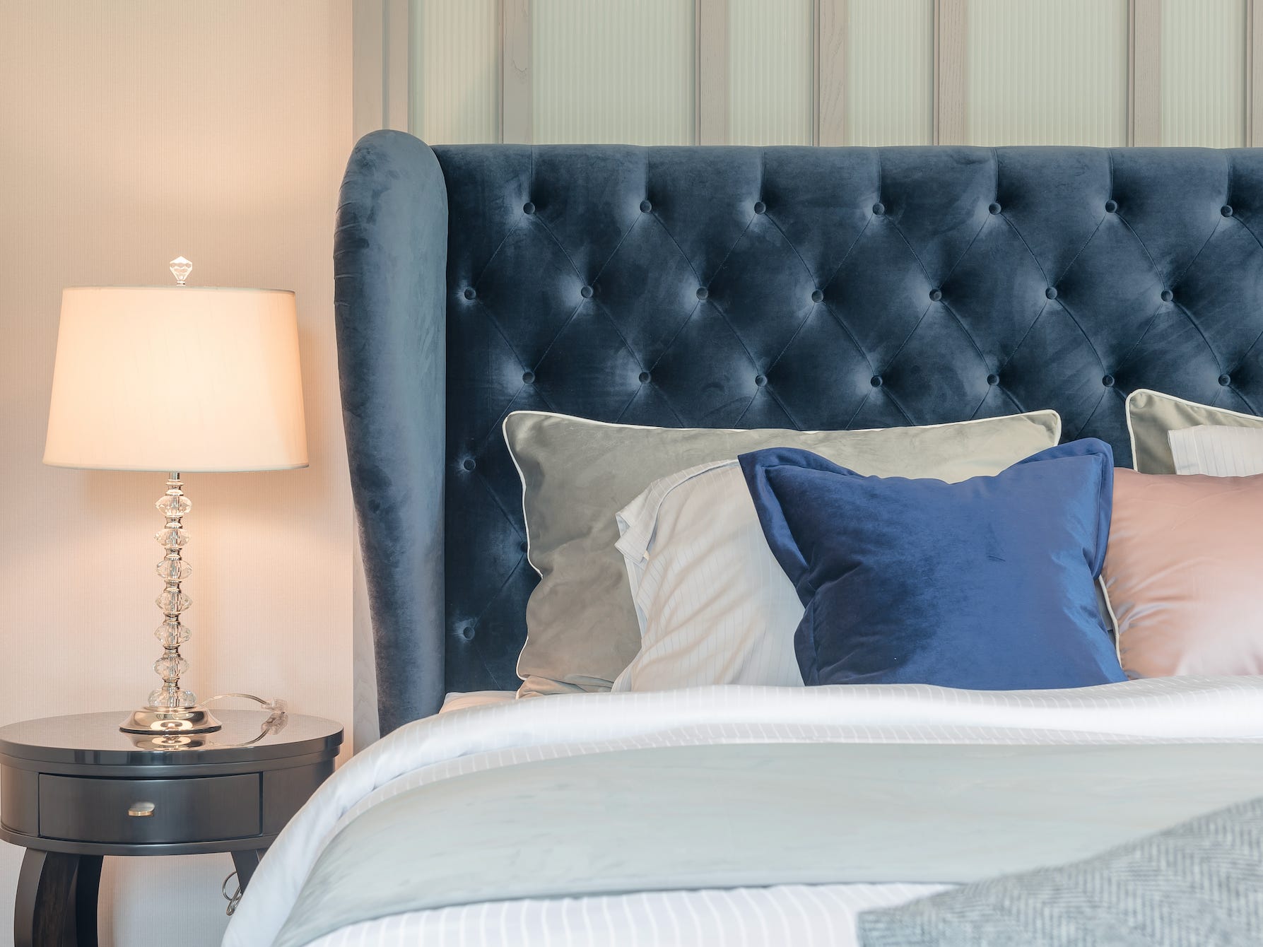Modernes Bett mit einem großen blauen gepolsterten Kopfteil und blauen und rosa Kissen