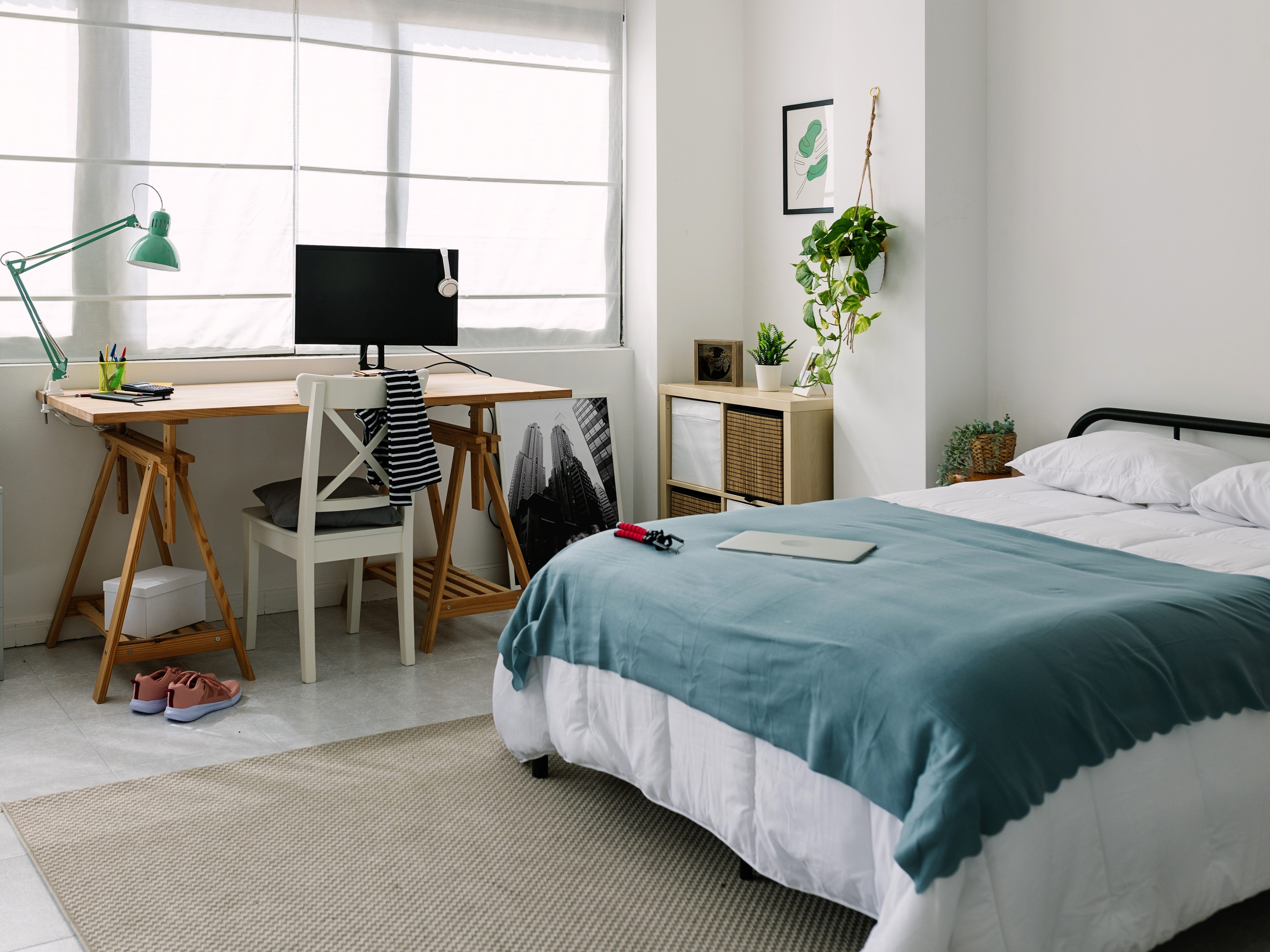 Sauberes, modernes Schlafzimmer mit Schreibtisch und Bett sowie blau-weißen Designdetails