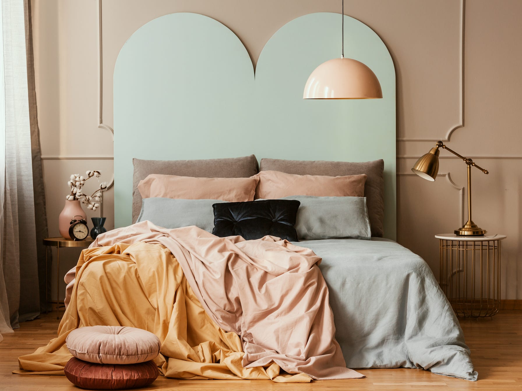 Modernes Schlafzimmer mit einem Bett mit großem Kopfteil und gelben, blauen und rosa Designdetails und Bettwäsche