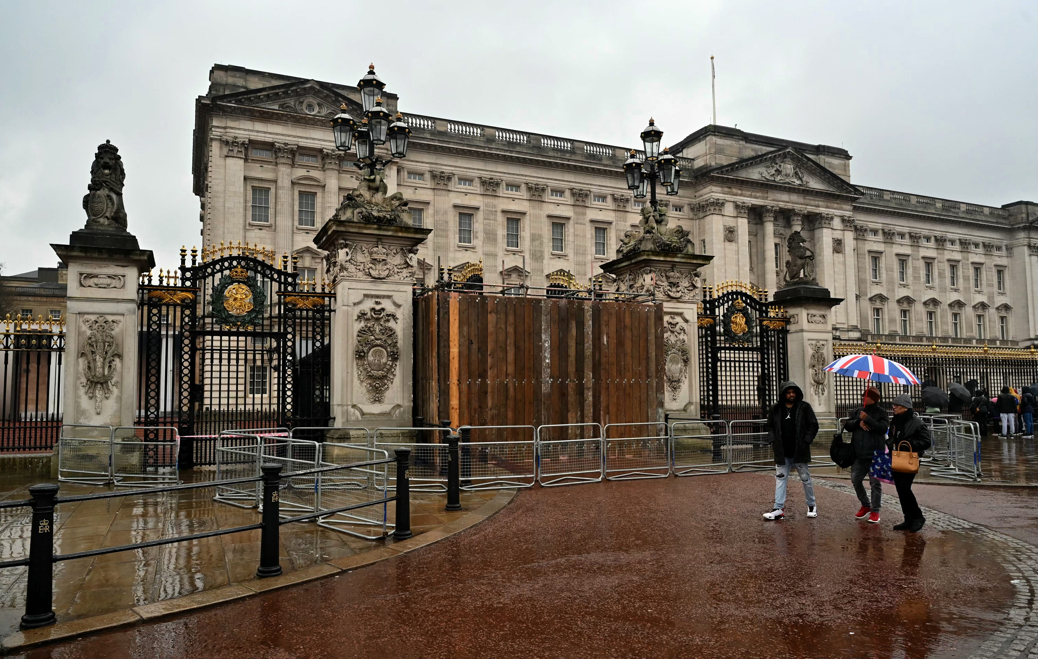 Menschen gehen am 10. März 2024 an einem mit Brettern vernagelten Tor zum Buckingham Palace in London vorbei.